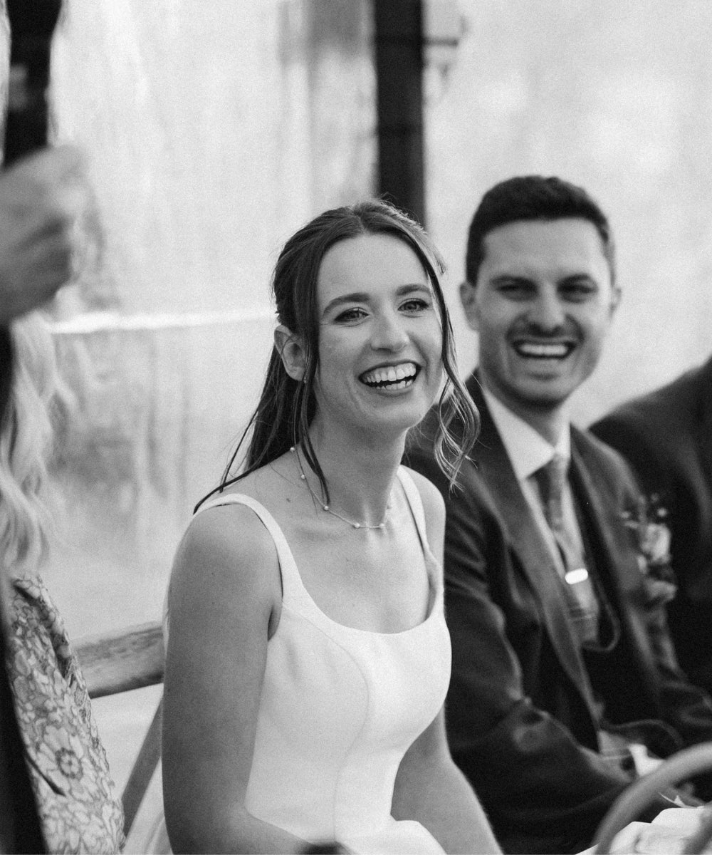 bride holding white rose bouquet wearing delicate pearl bracelet, black and white wedding photography