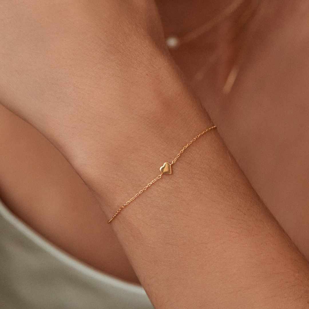 Gold tiny heart bracelet on a wrist