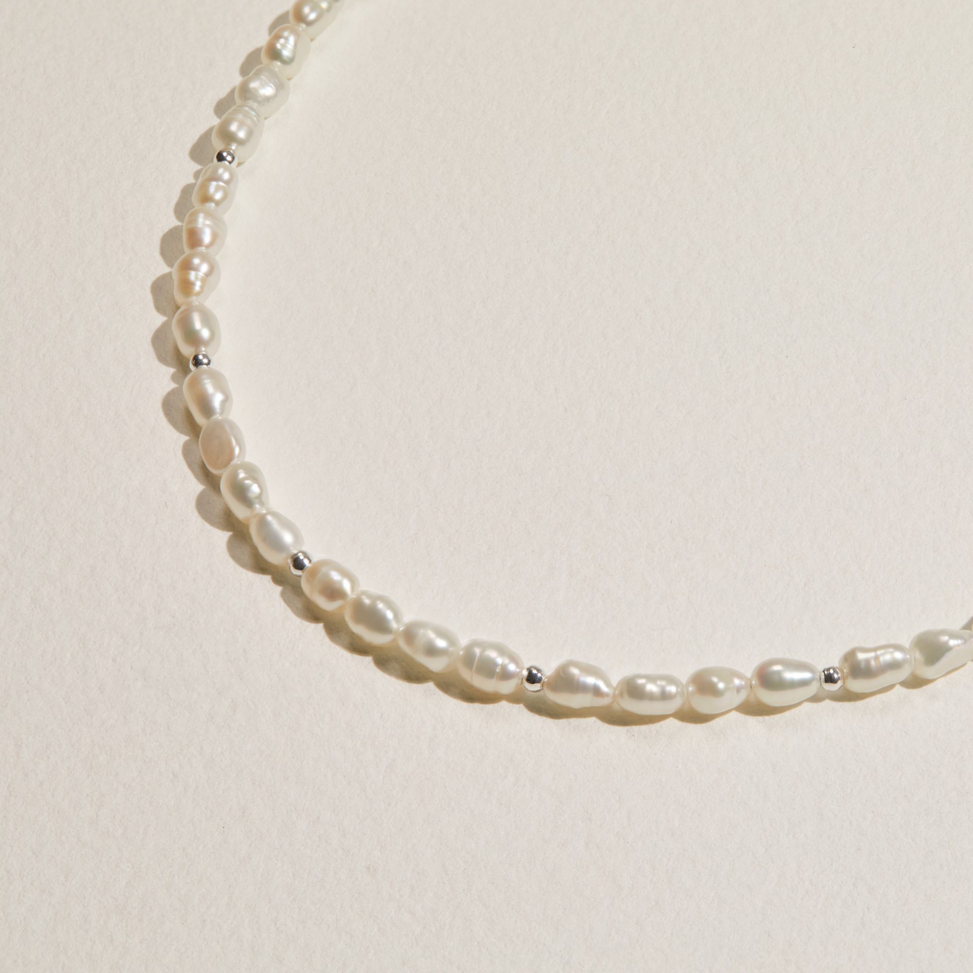 Silver beaded seed pearl choker on a paper surface