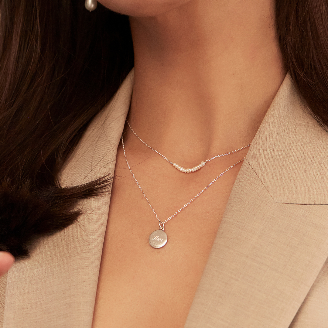 Silver small pearl cluster choker around a neck of a woman wearing a beige blaser