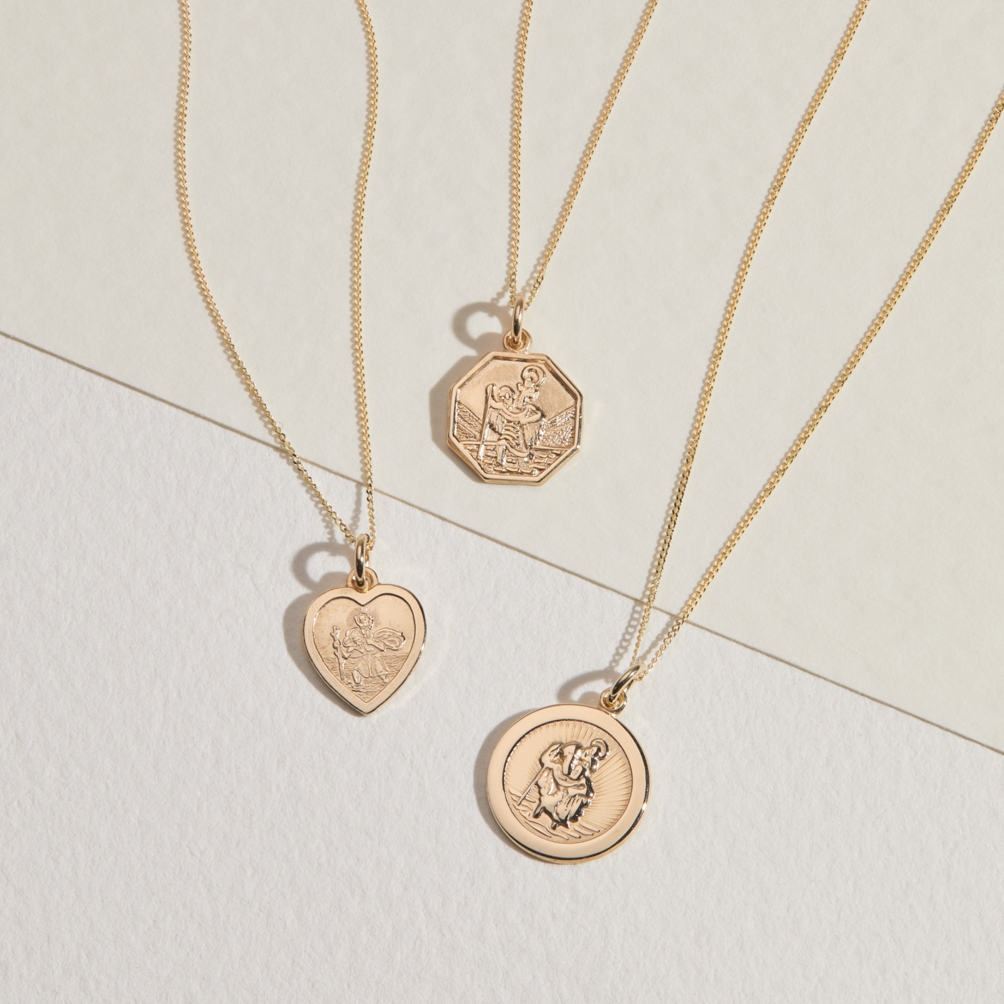 Gold small heart st christopher necklace, alongside a small circle st christopher necklace and a small octagonal st christopher necklace