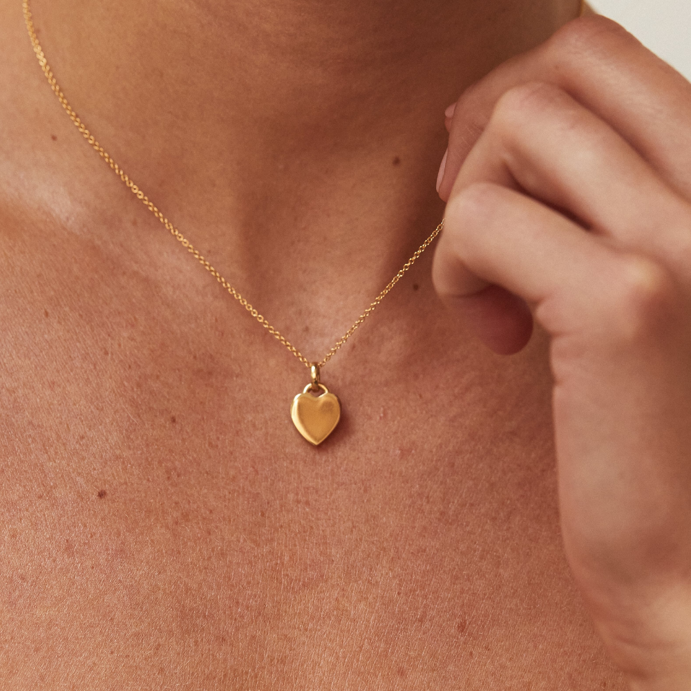 Gold heart padlock pendant necklace around a neck with fingers clasping the chain