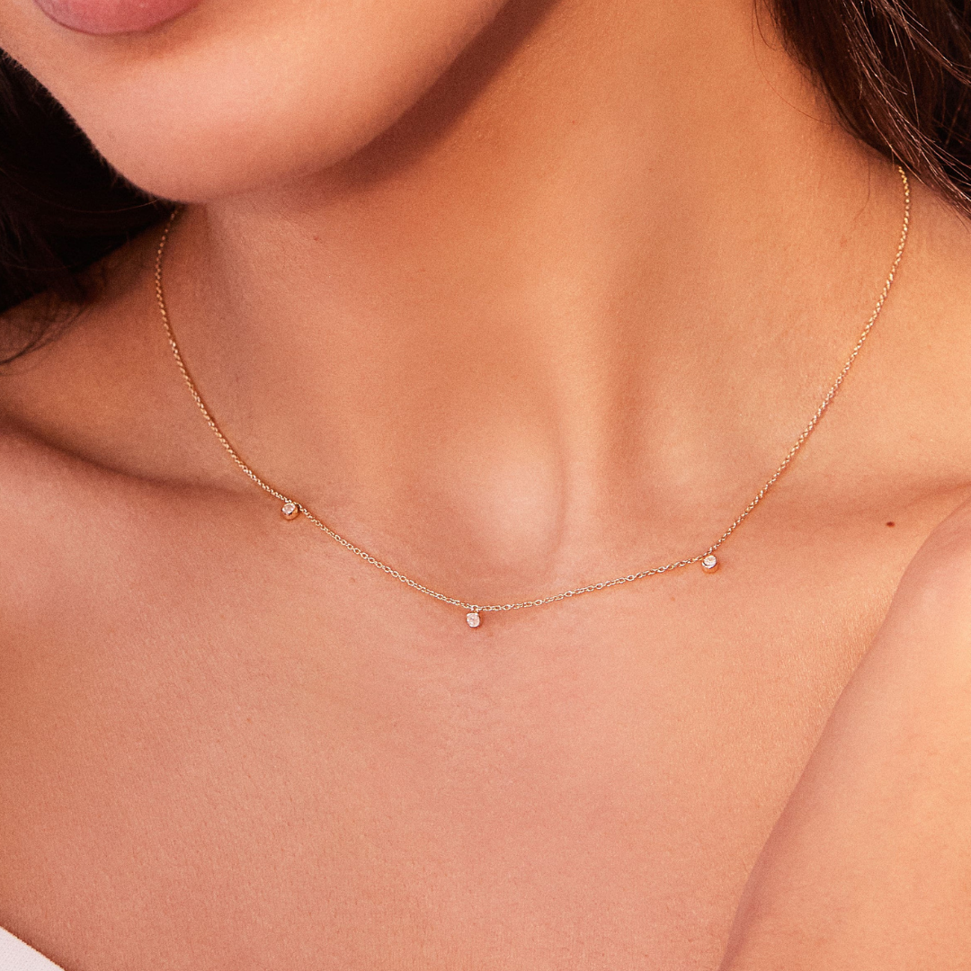 Solid gold diamond drop necklace around a neck close up