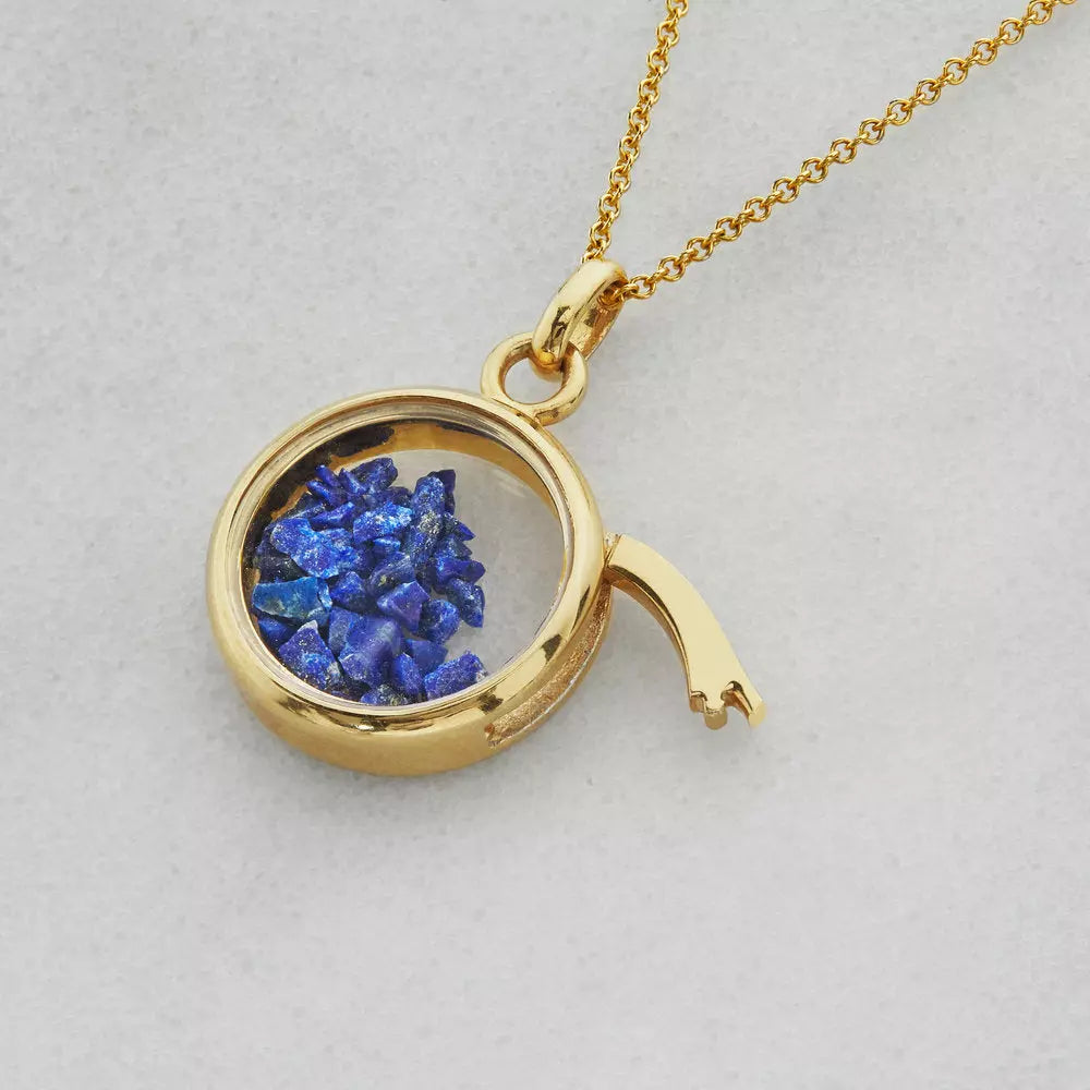 Gold glass gemstone locket with deep blue gemstones on a grey background