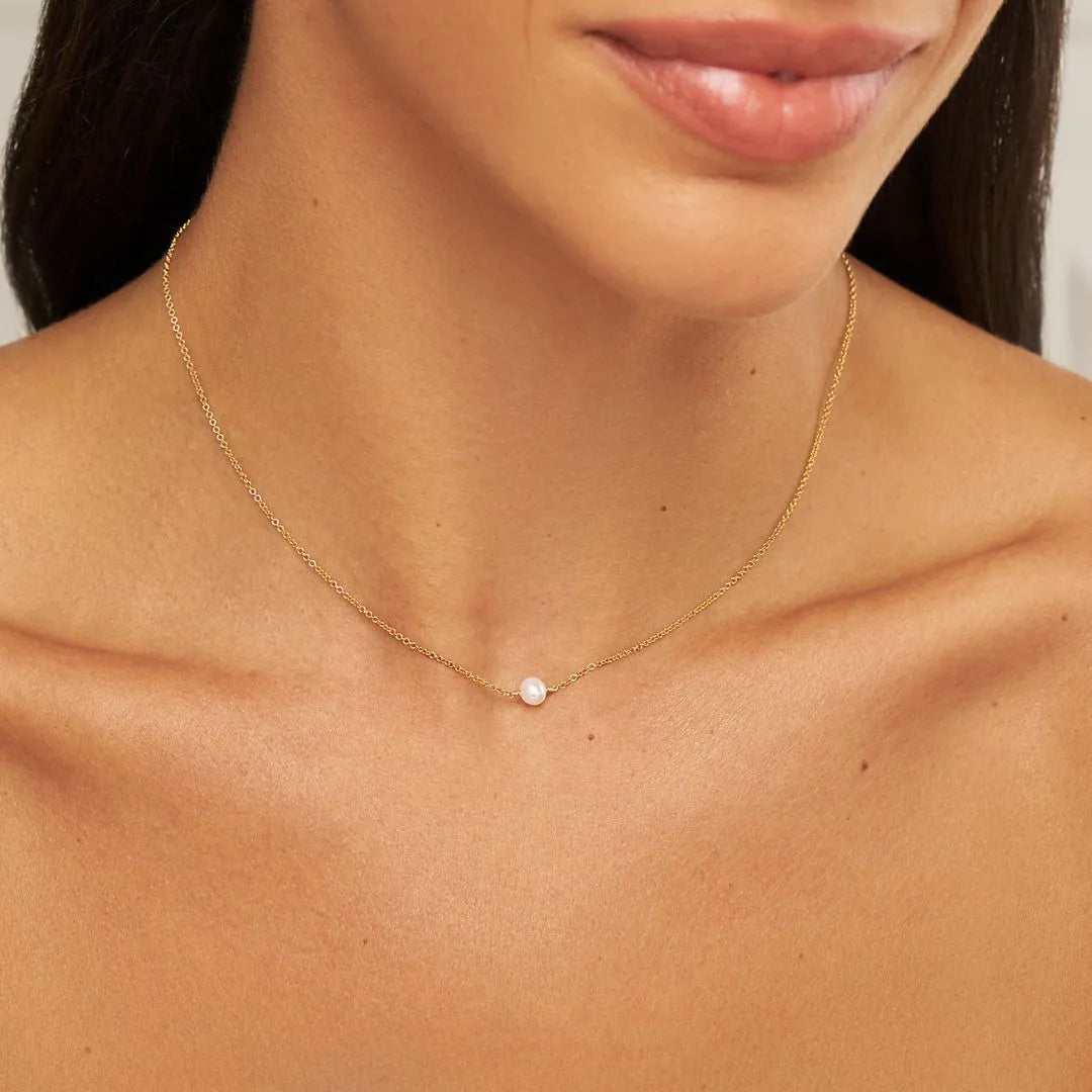 Close up shot of gold single pearl choker on a neck