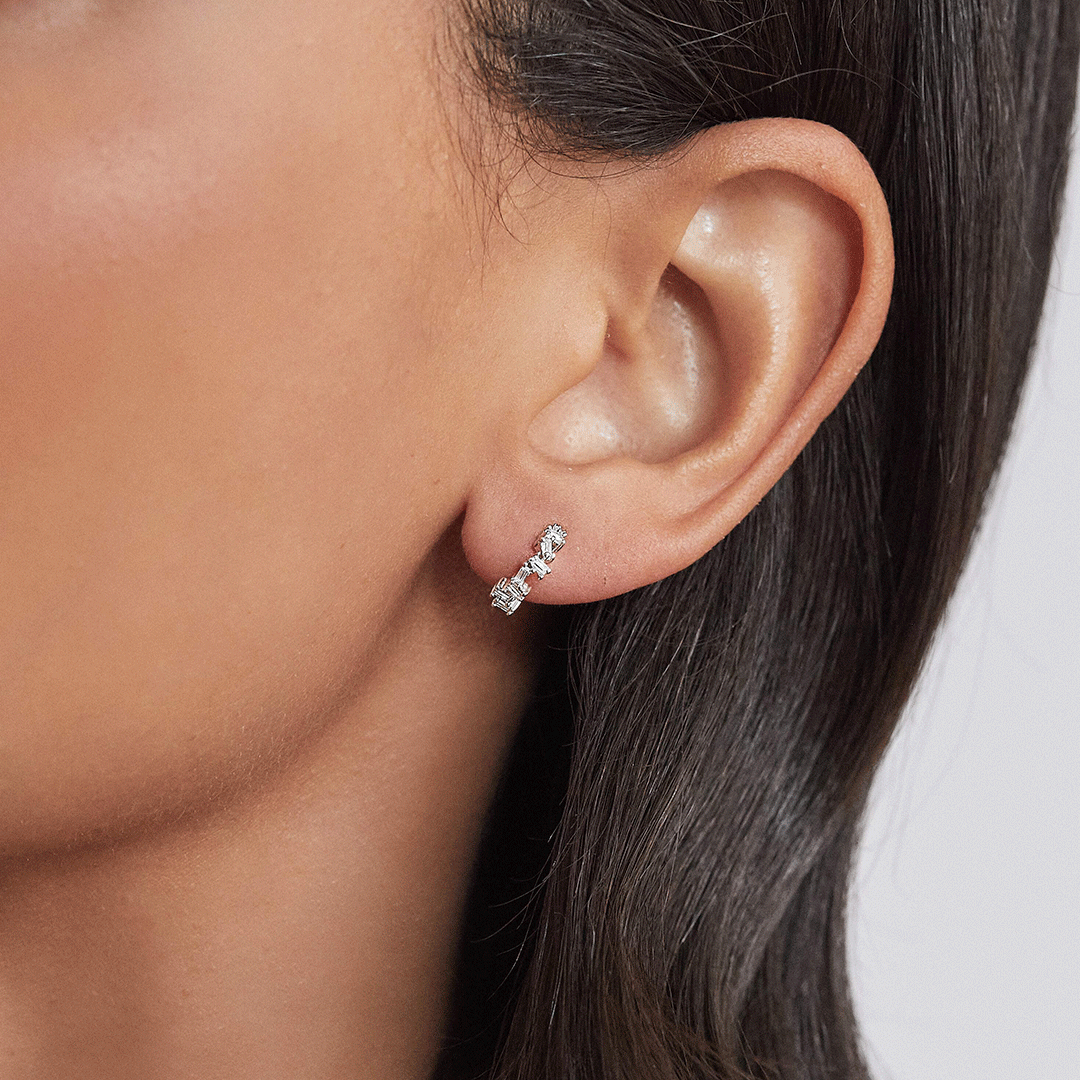 Silver diamond style jagged huggie hoop earring in an ear lobe