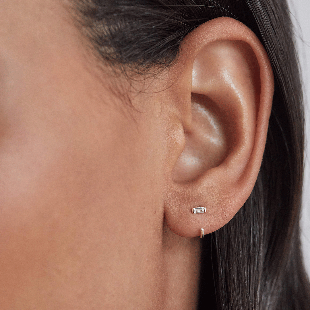 Silver diamond style baguette lobe hoop earring in one ear lobe close up