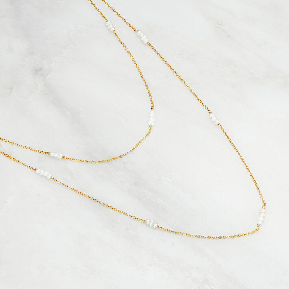Gold layered mini pearl necklace on a marble surface