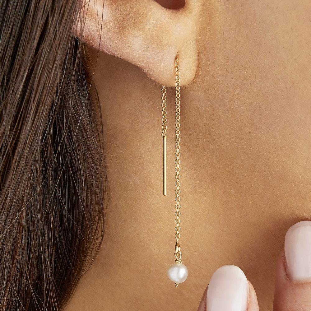 Gold pearl drop ear threader in one ear lobe close up