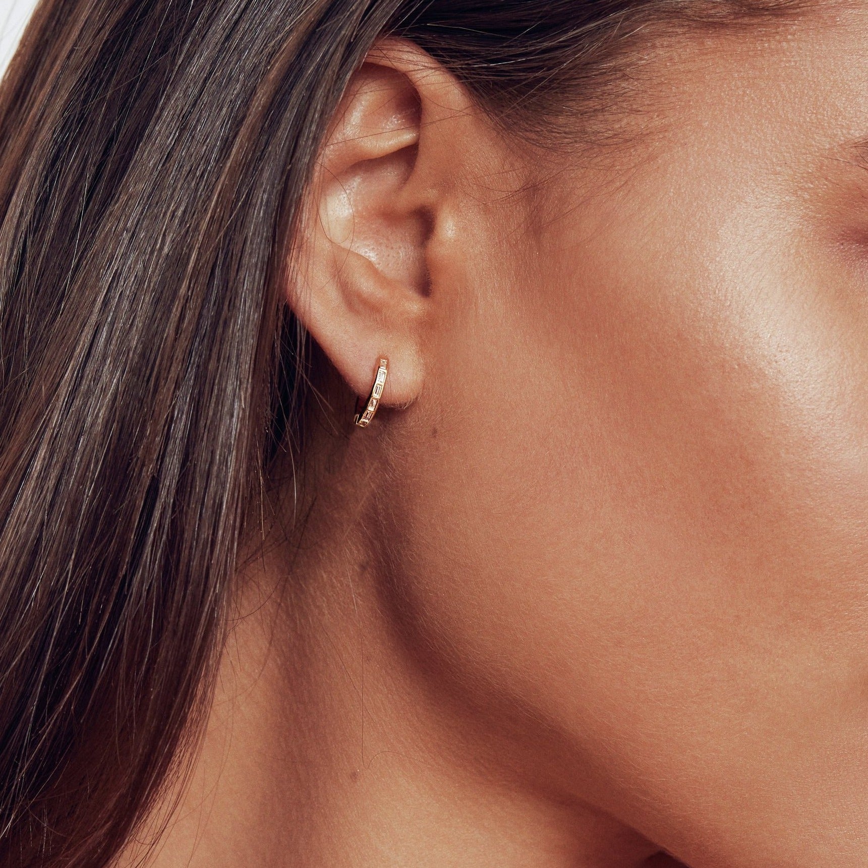 Gold diamond style baguette pearl drop hoop earring in one ear lobe with pearl removed