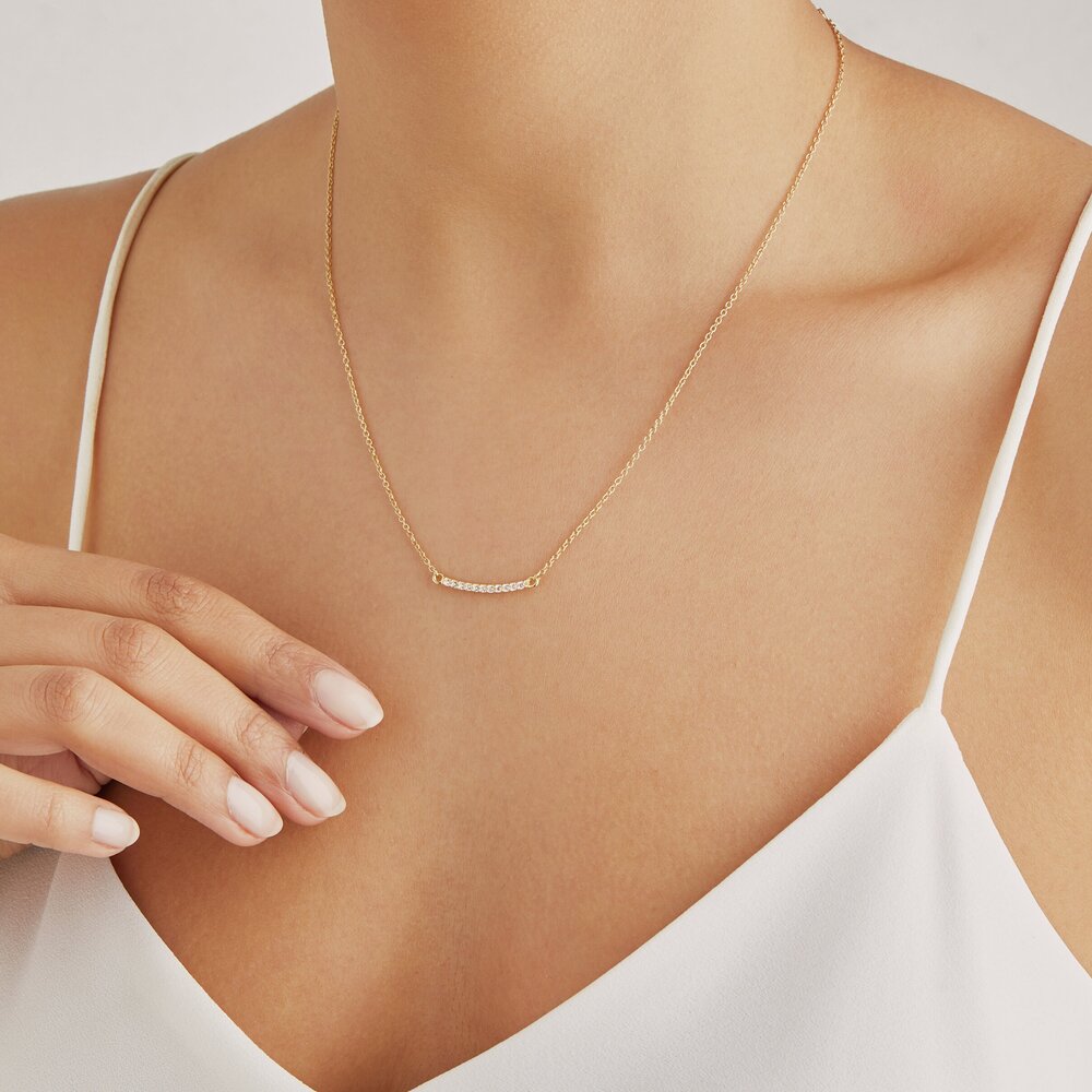 Gold diamond style bar necklace on chest with white top