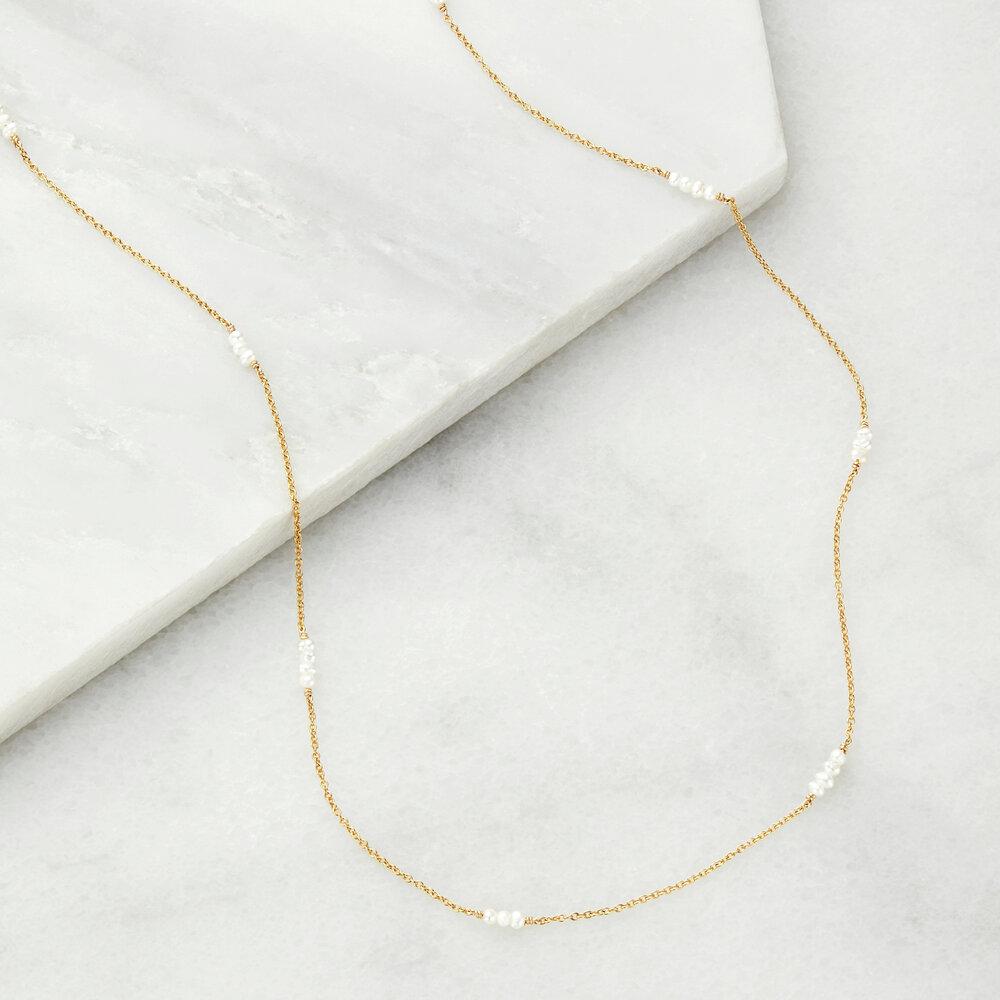Gold mini pearl necklace on marble surfaces