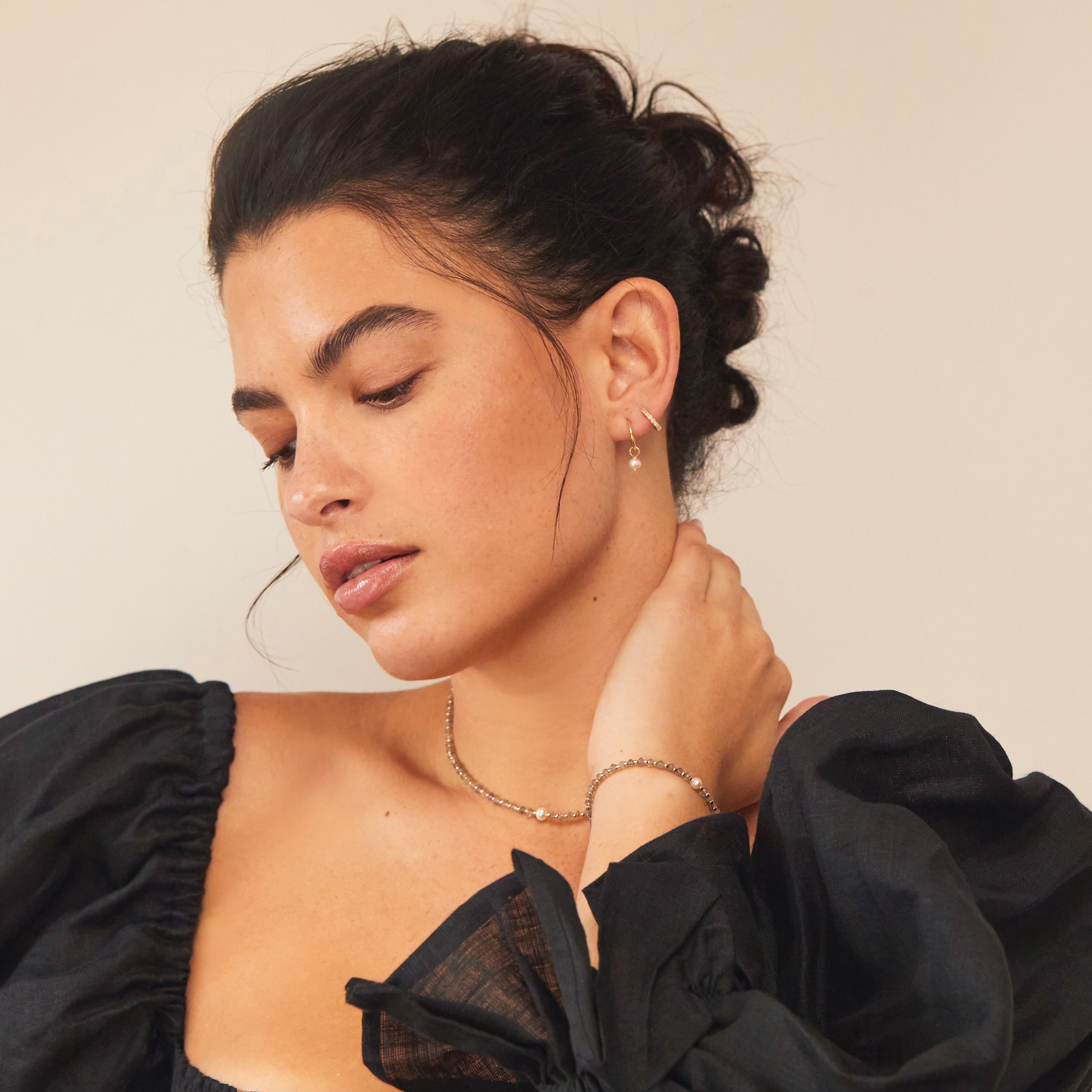 Gold labradorite gemstone bracelet on a brunette woman's wrist with a gold labradorite gemstone choker around the neck with a pearl and diamond style earing in the ear lobe