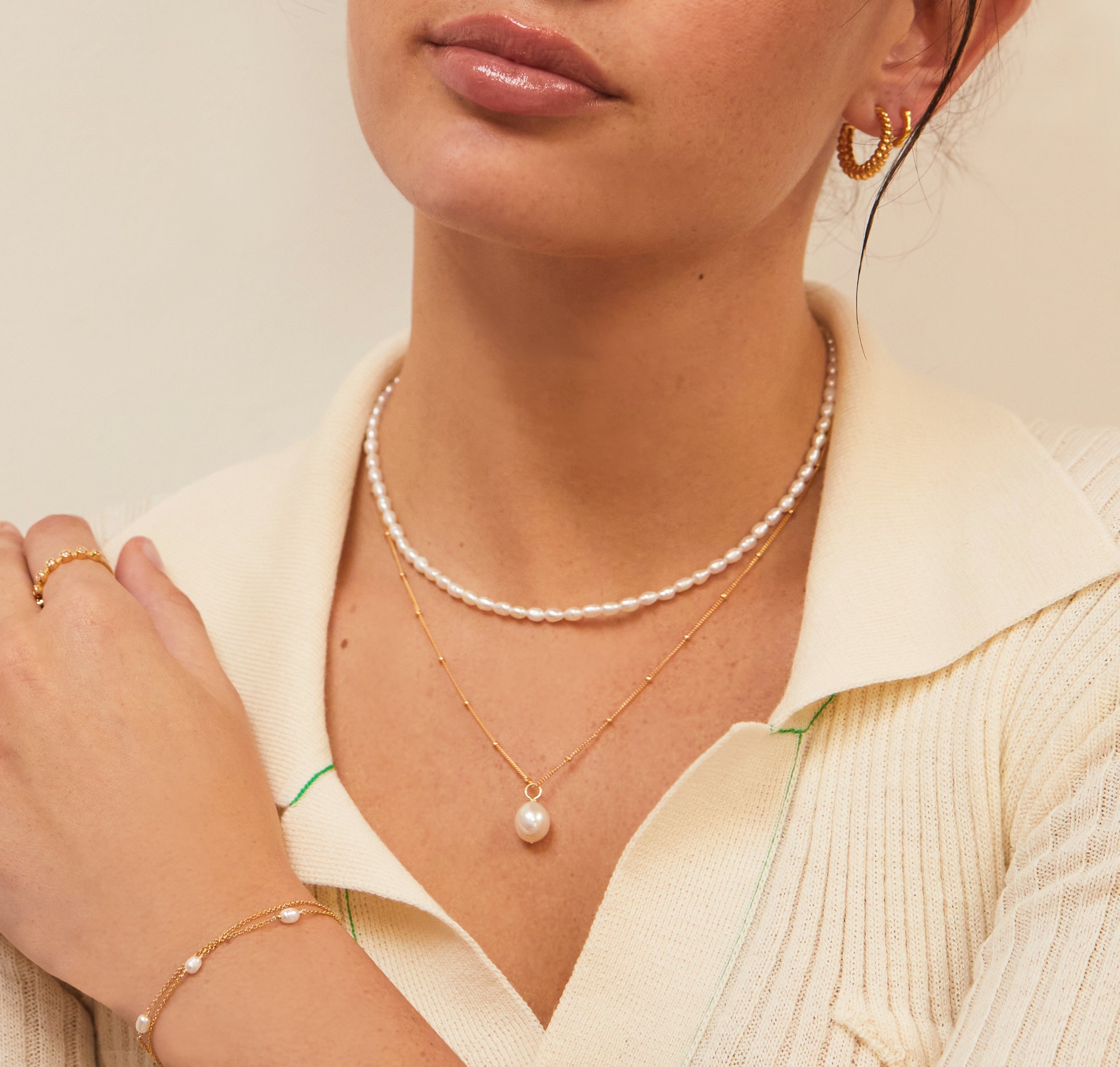 Gold large pearl satellite necklace and pearl chocker on a woman with a cream collared shirt