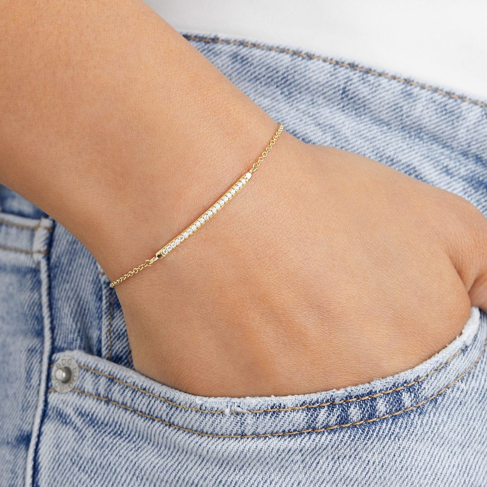 Silver diamond style bar bracelet on a wrist with the hand in a blue denim pocket