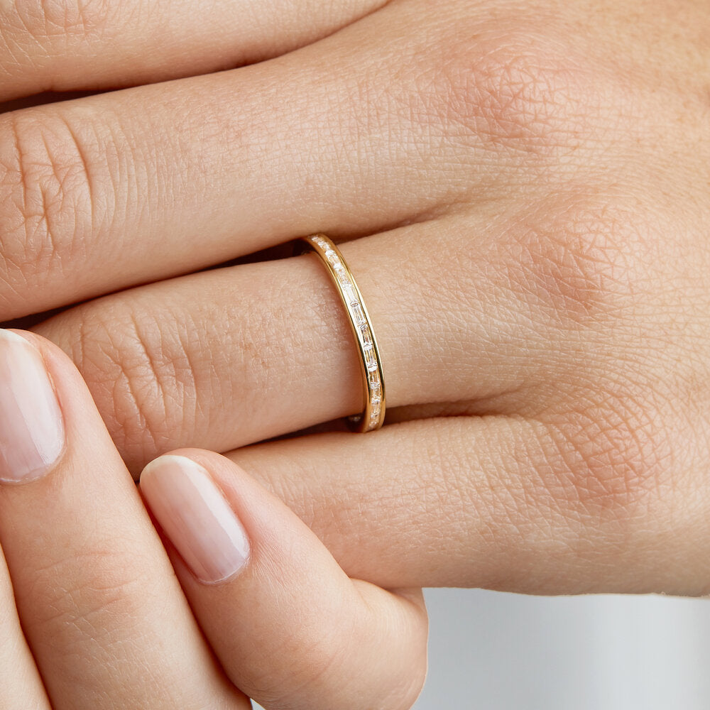 Gold diamond style baguette eternity ring on a finger close up