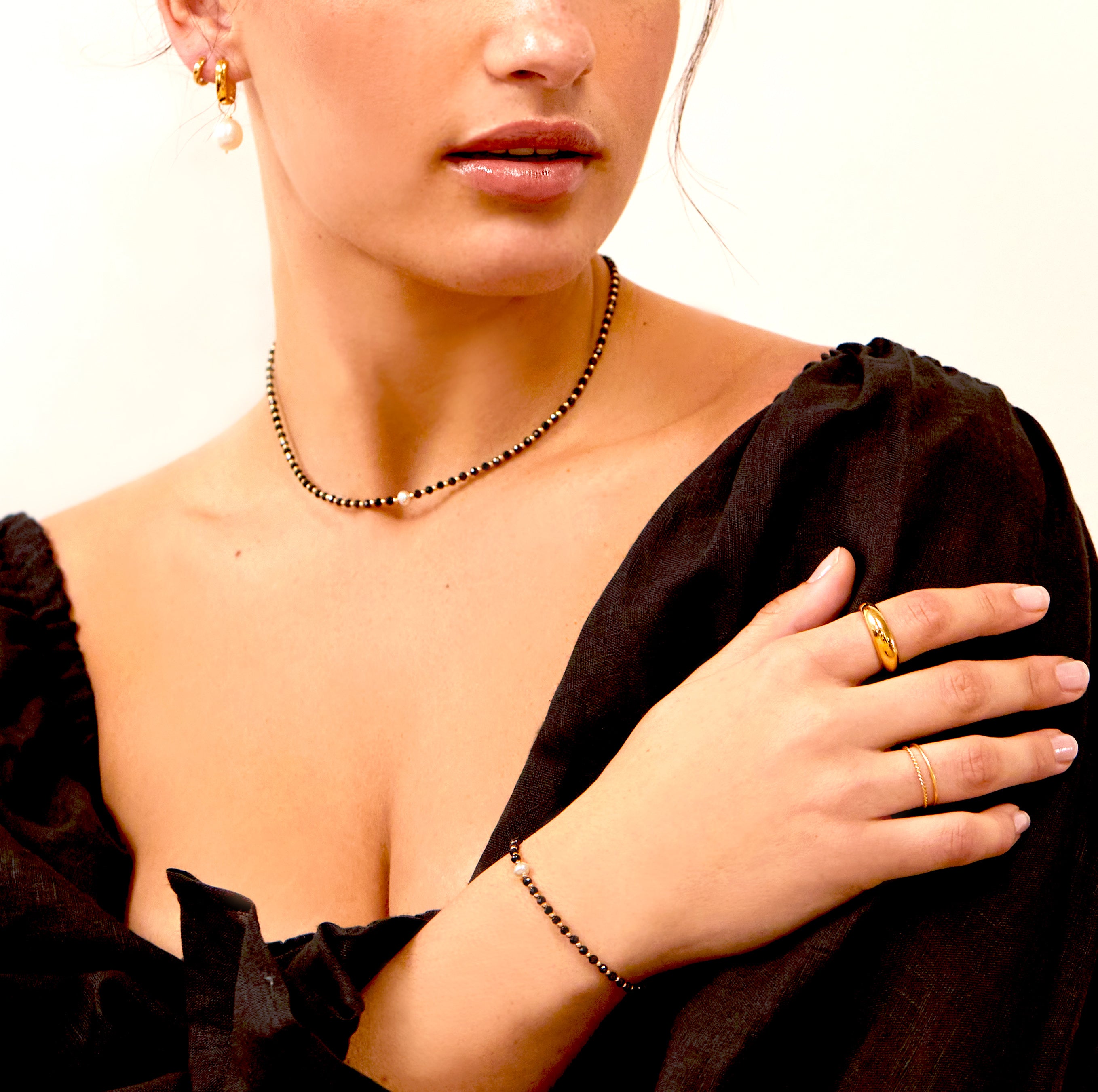 Gold spinel gemstone bracelet on a woman's wrist paired with a gold spinel gemstone choker and a gold ring