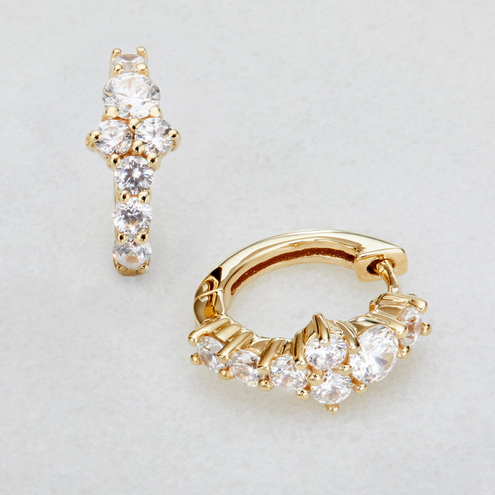 Gold diamond style cluster huggie hoop earrings on a marble surface