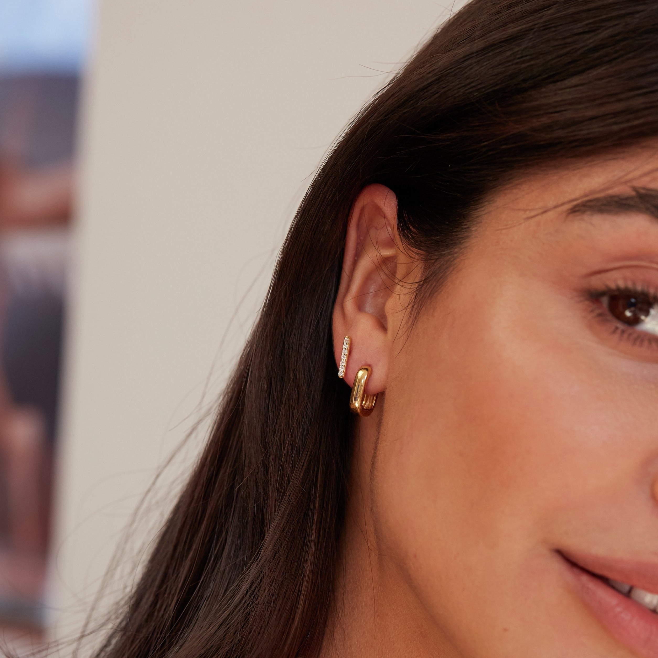 Gold diamond style bar stud earring with gold cuff in one ear lobe