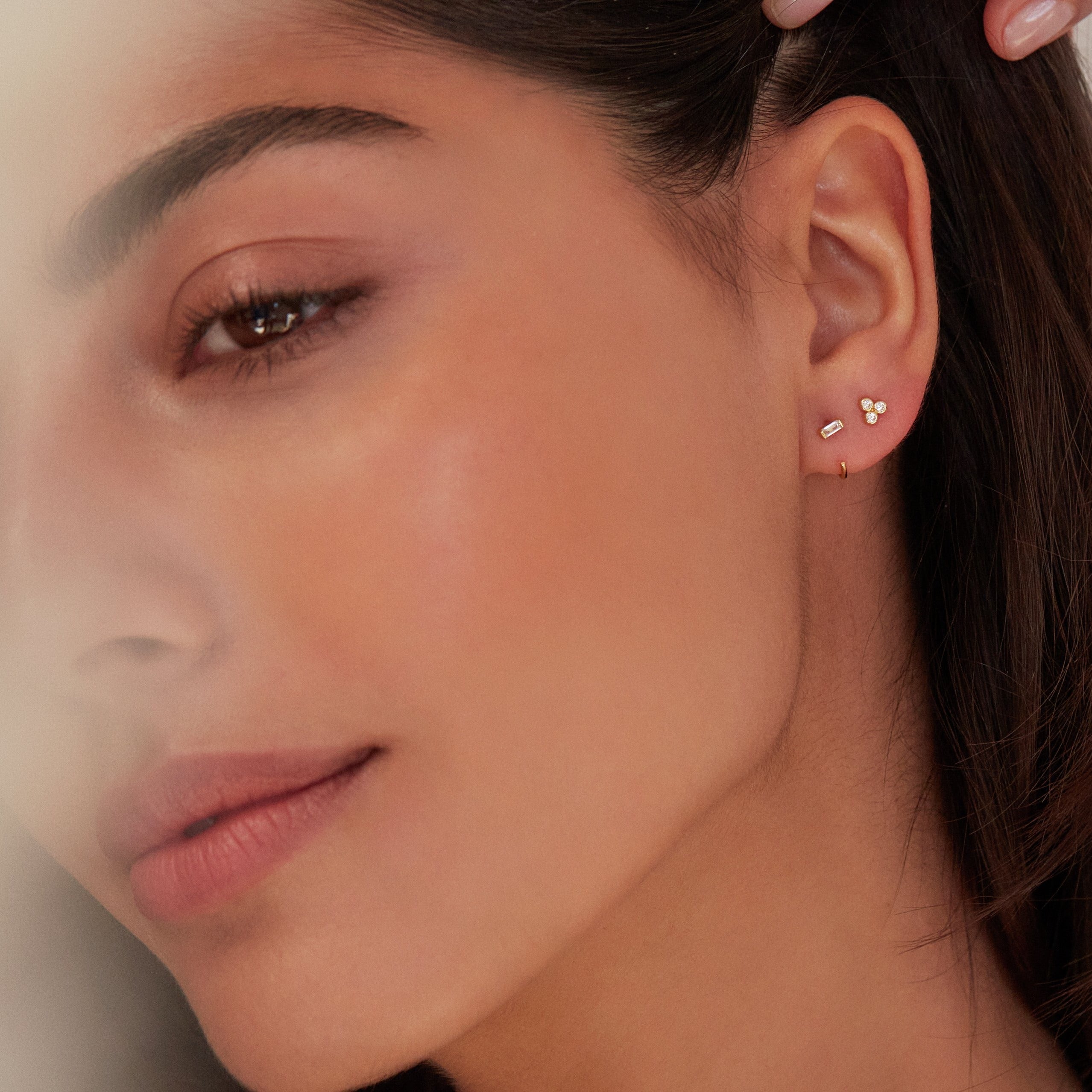 Gold diamond style baguette lobe hoop earring with gold diamond style pyramid stud earring in one ear lobe 