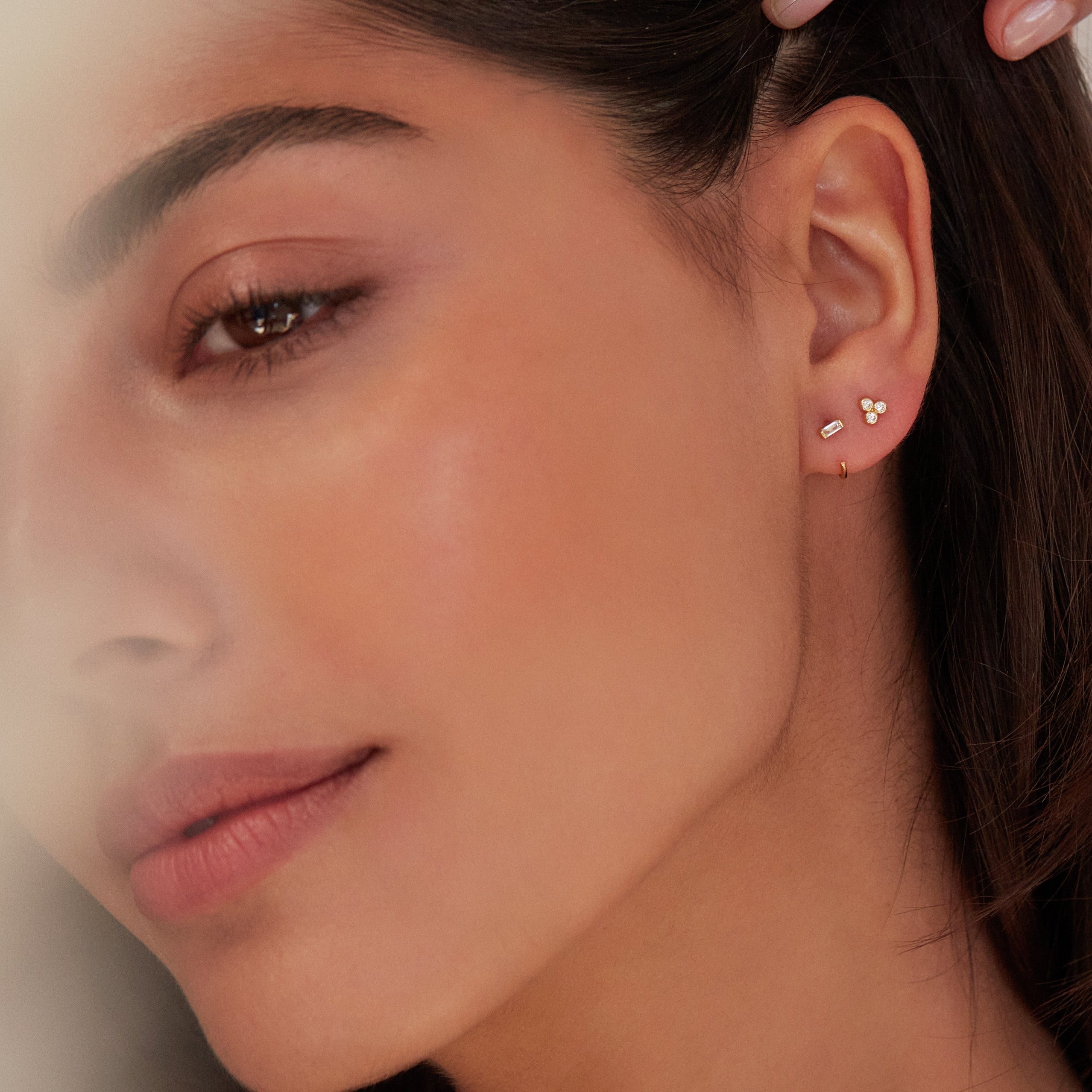 Gold diamond style baguette lobe hoop earring with gold diamond style pyramid stud earring in one ear lobe