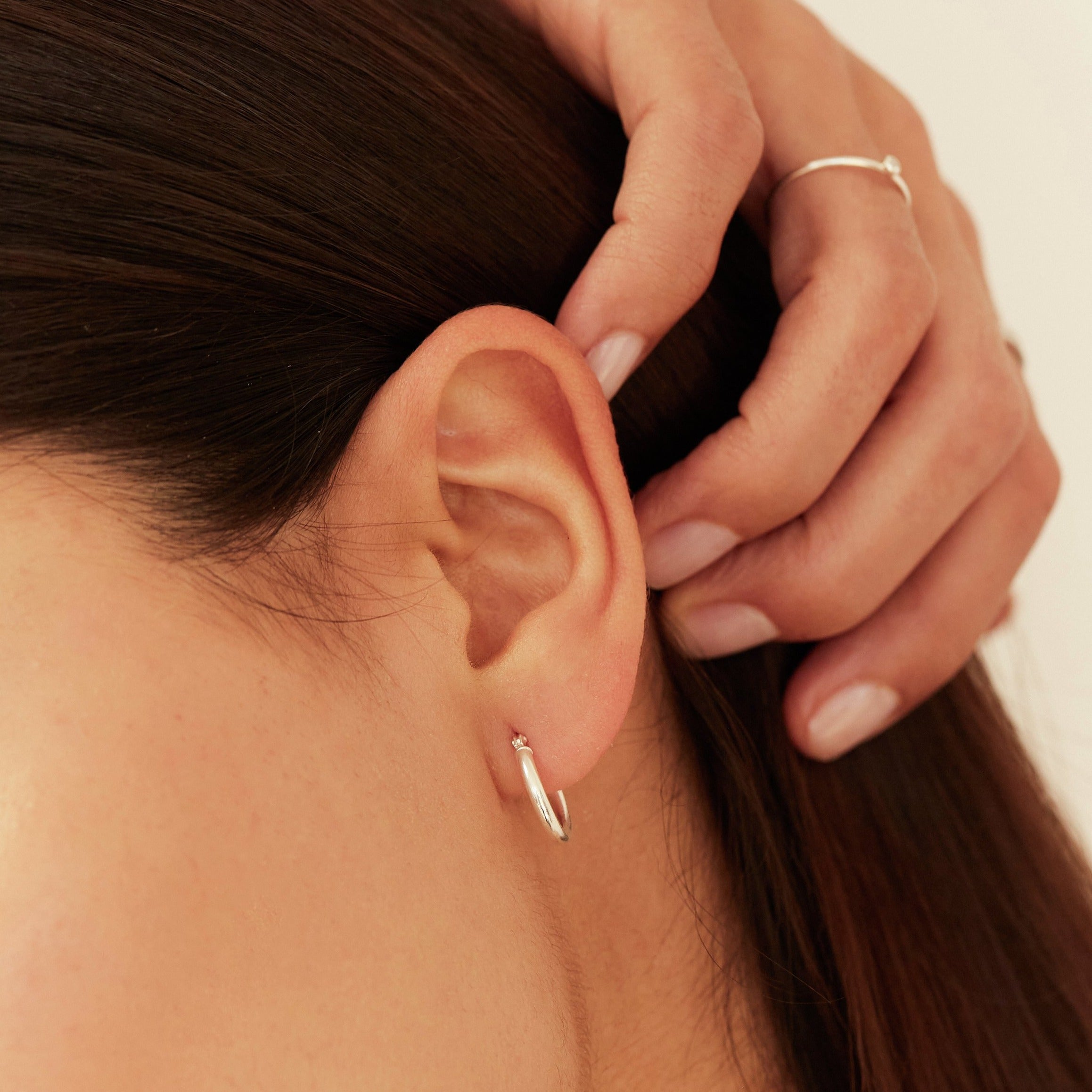 Silver small rounded hoop earring in one ear lobe