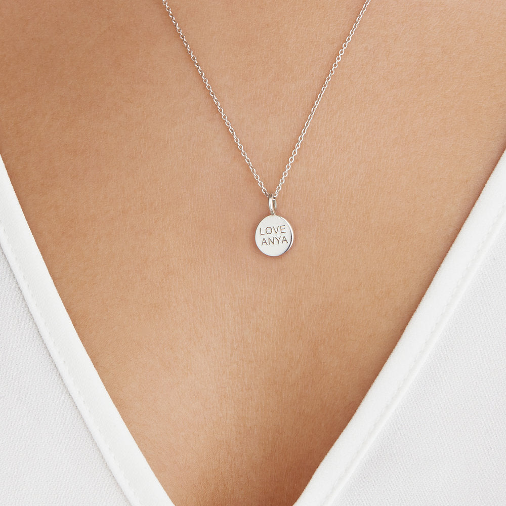 Silver small personalised disc necklace with 'LOVE ANYA' engraved on a woman's chest