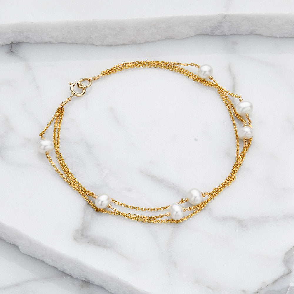 Gold layered pearl bracelet on marble surfaces
