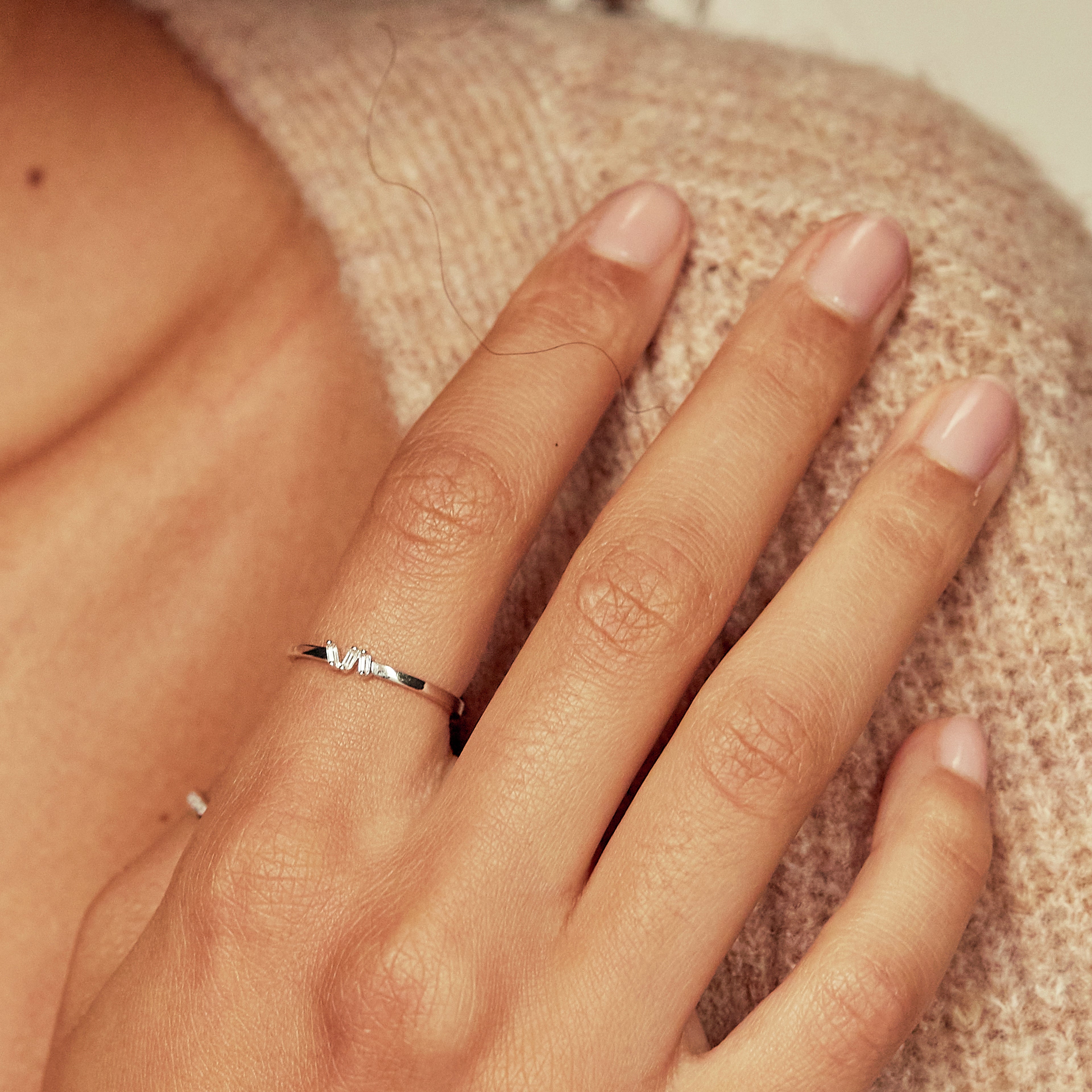 Gold diamond style three baguette ring on hand with a brown jumper
