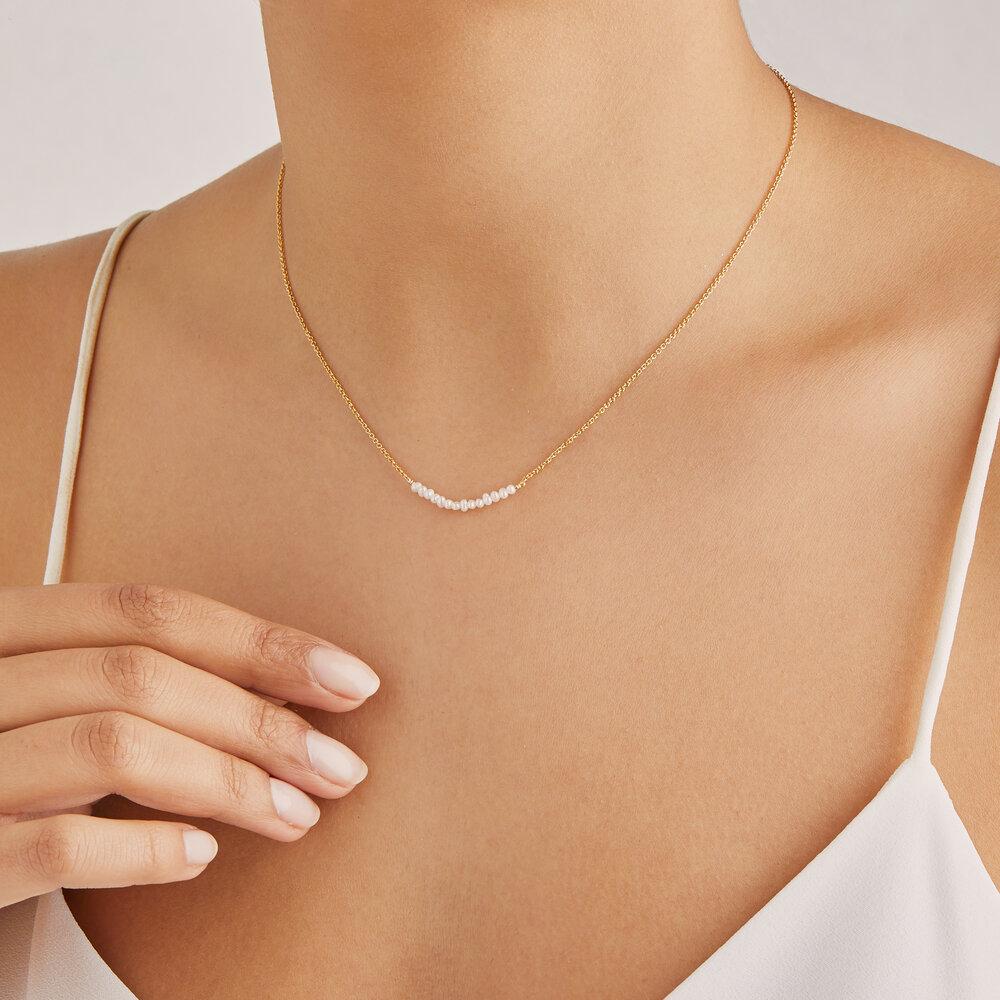 Gold small pearl cluster choker around a neck with a white top