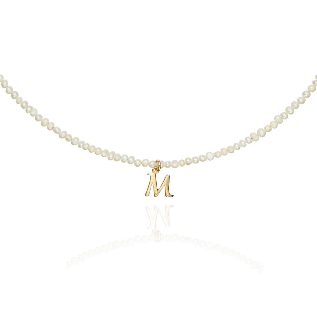 Bottom part of a gold small pearl initial letter choker on a white background