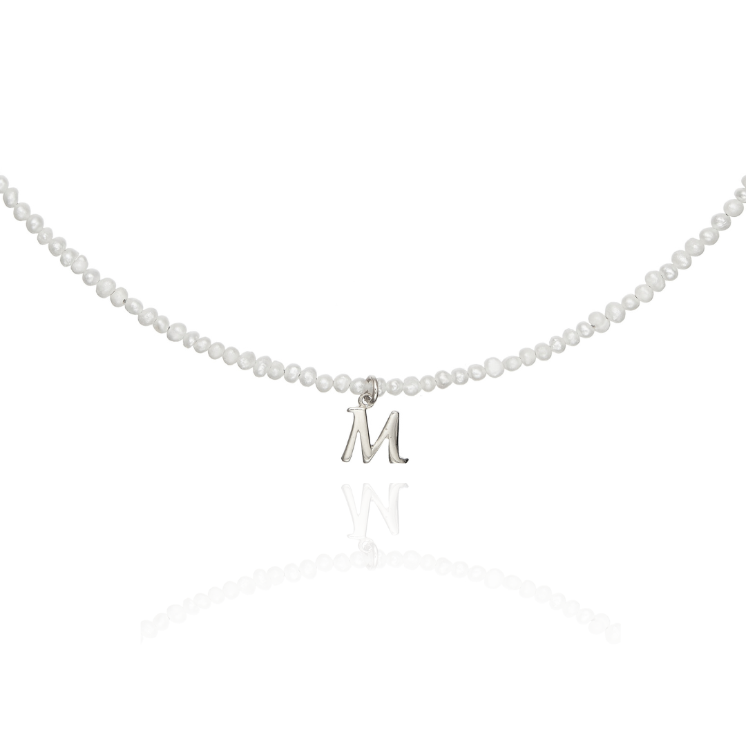 Close up of silver small pearl initial letter choker 'M' on a white background
