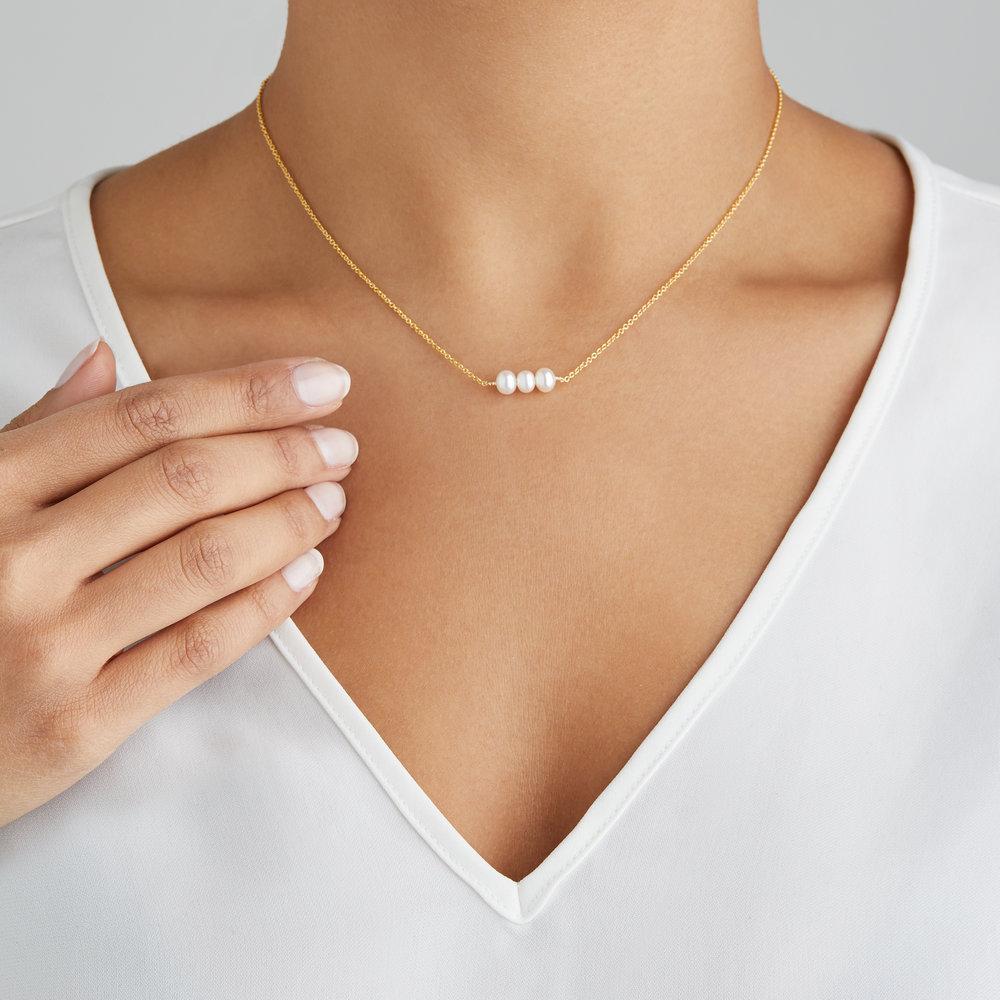 Gold cluster pearl choker on a neck with a white V-neck top