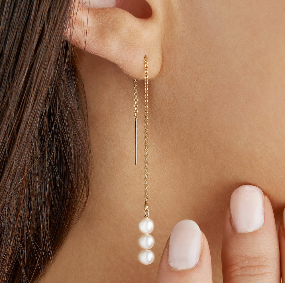 Gold cluster pearl drop ear threader close up in one ear lobe