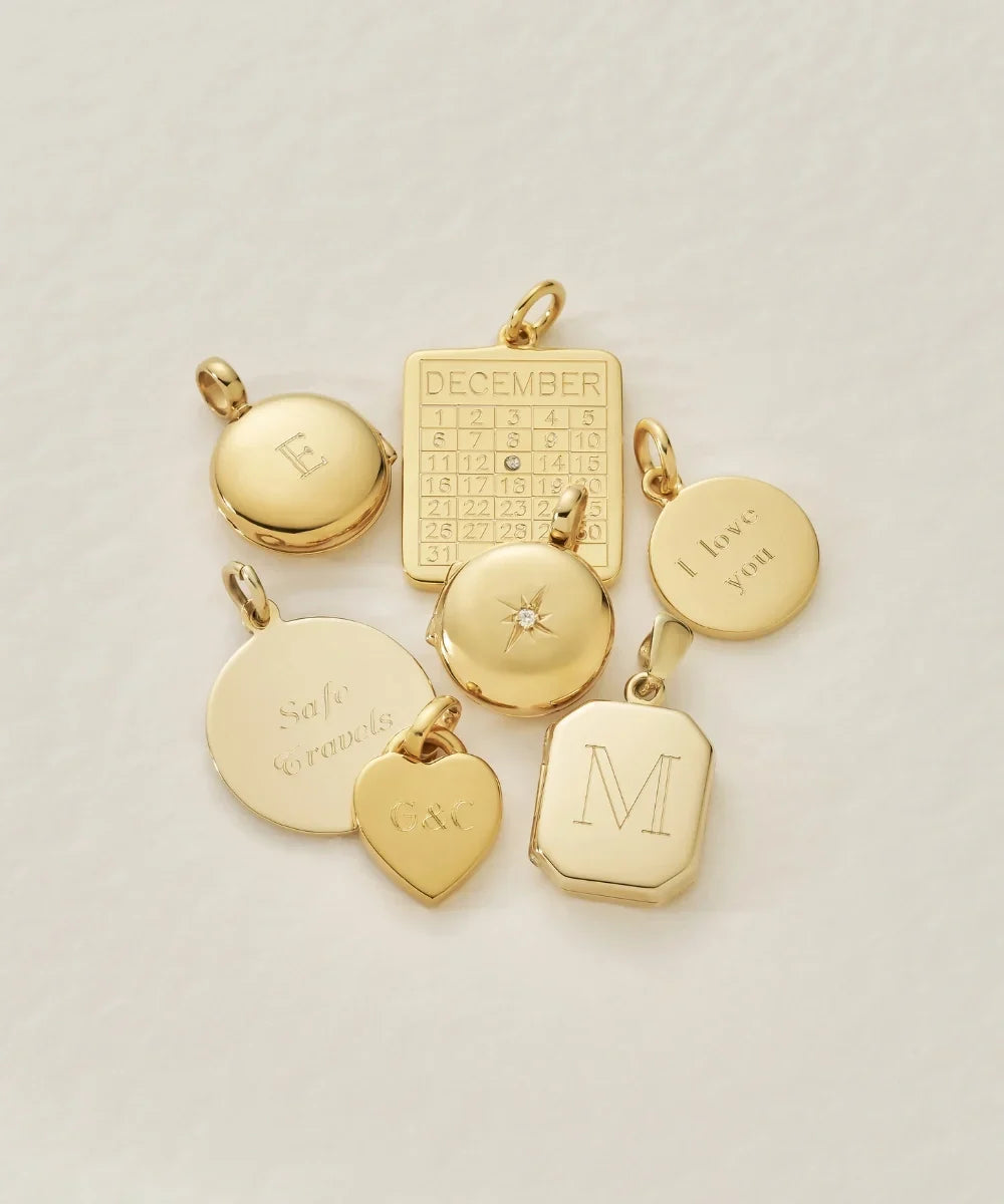 Close-up of gold personalised pendants featuring engraved initials, dates and meaningful messages.