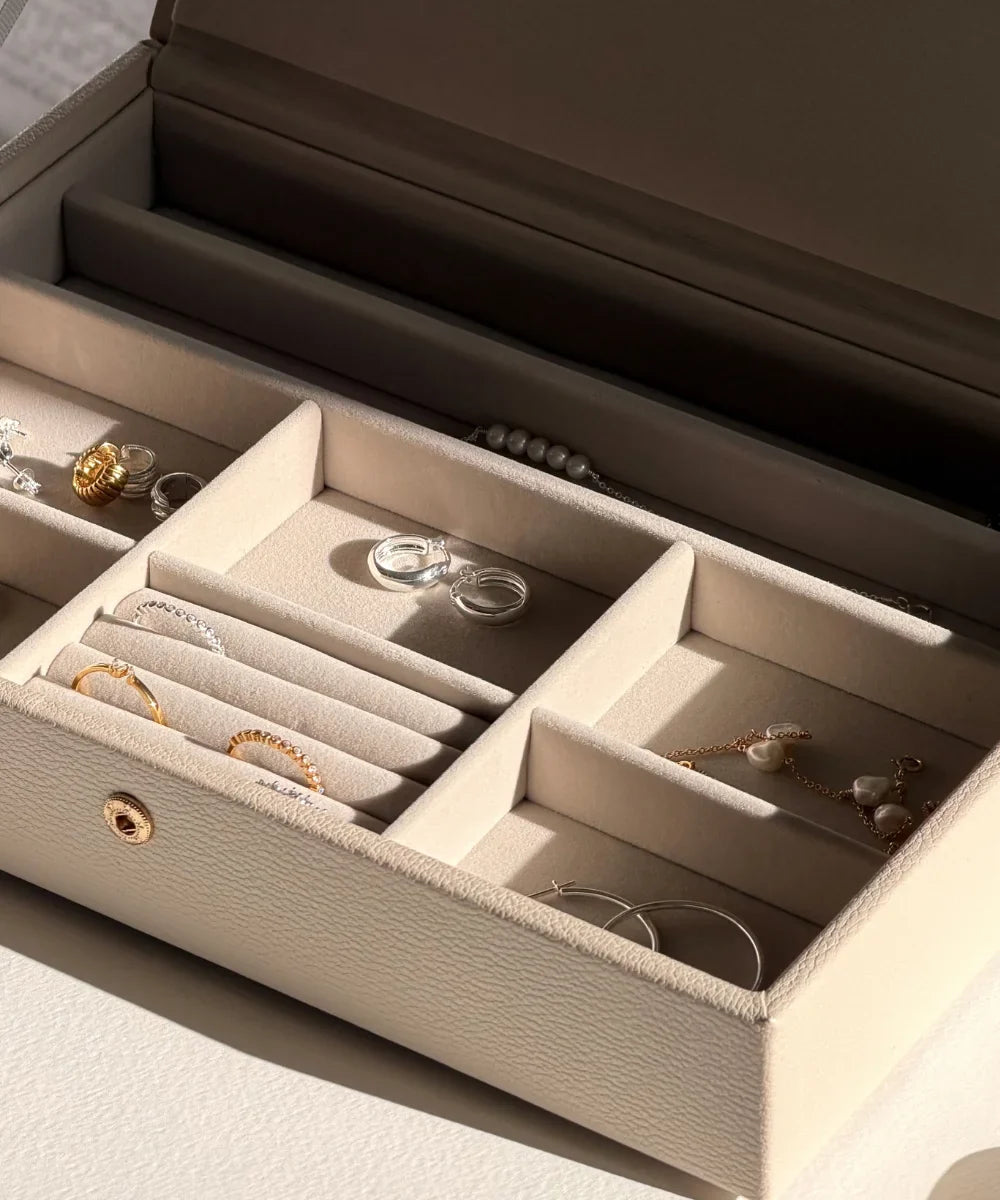 Open jewellery box with gold and silver rings, earrings and pearl jewellery neatly stored in separate compartments.