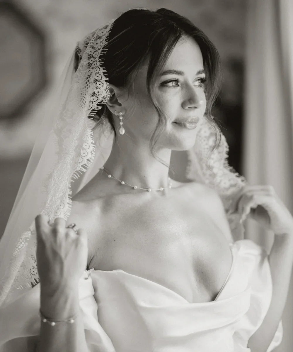 Black-and-white bridal portrait of Francesca wearing pearl drop earrings, a delicate necklace and a lace veil.