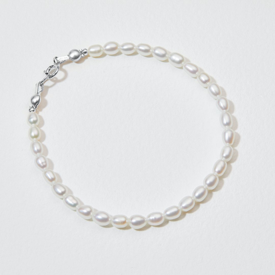 Silver seed pearl bracelet on a white paper surface
