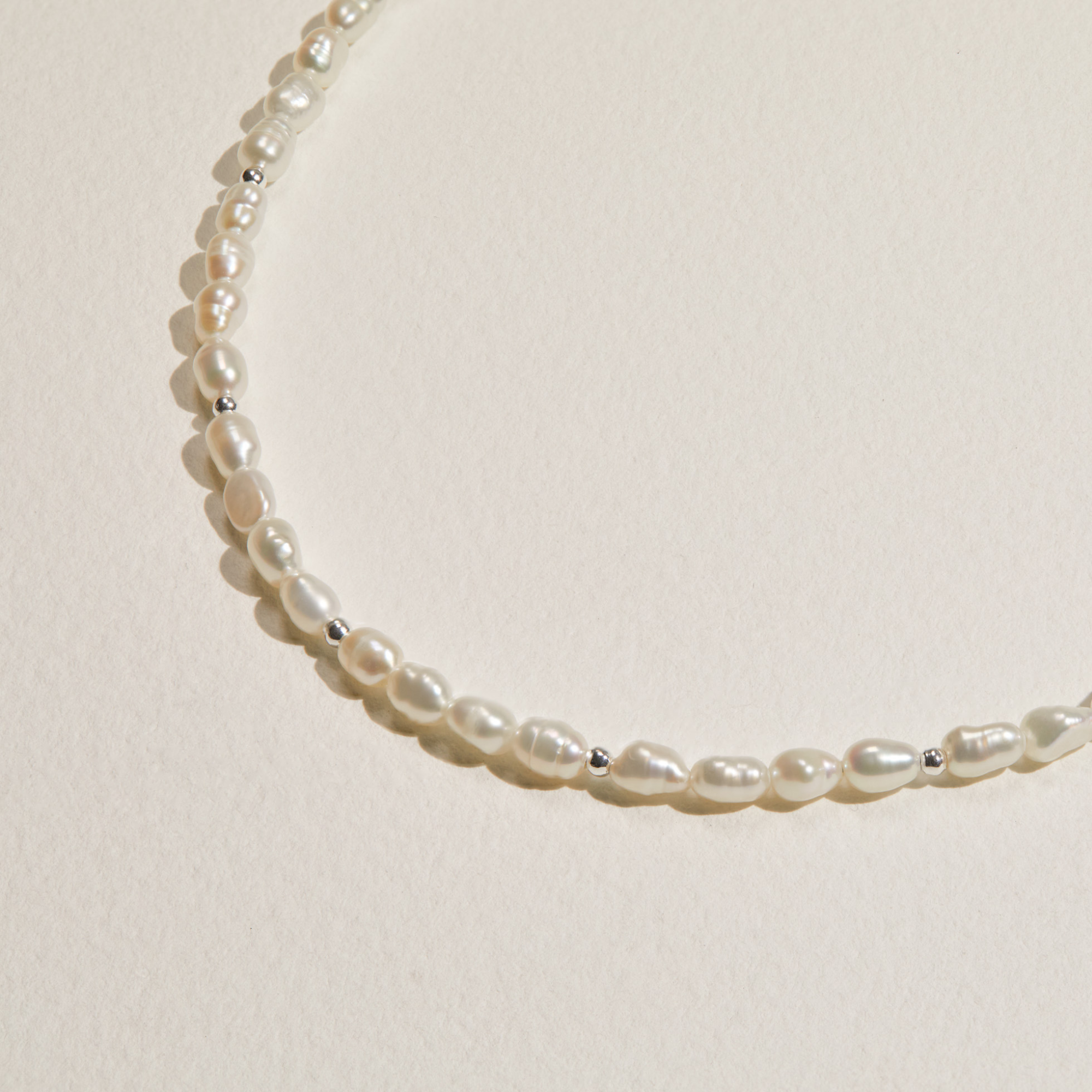 Close up gold beaded seed pearl choker on a white surface