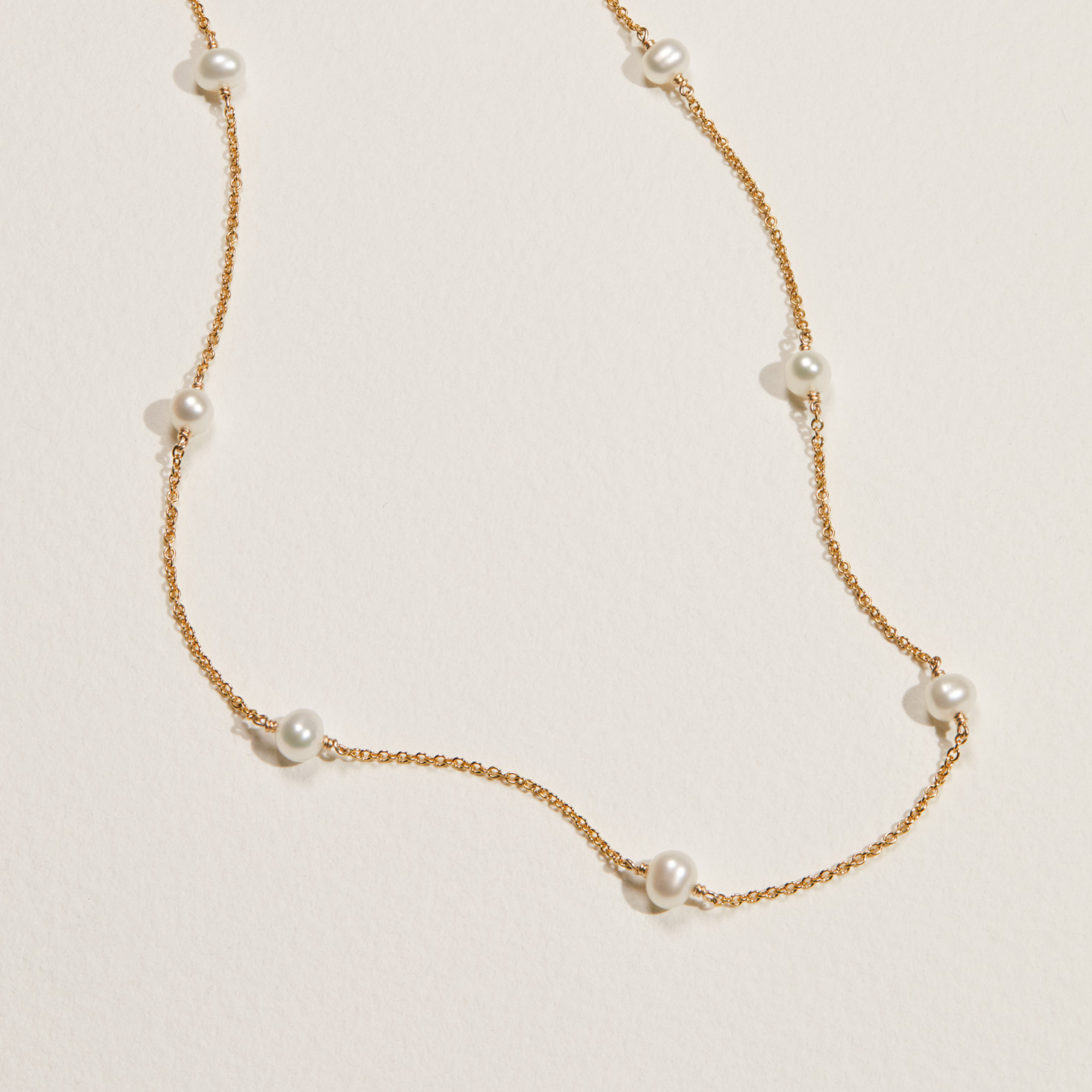 Gold ten pearl choker on a white surface