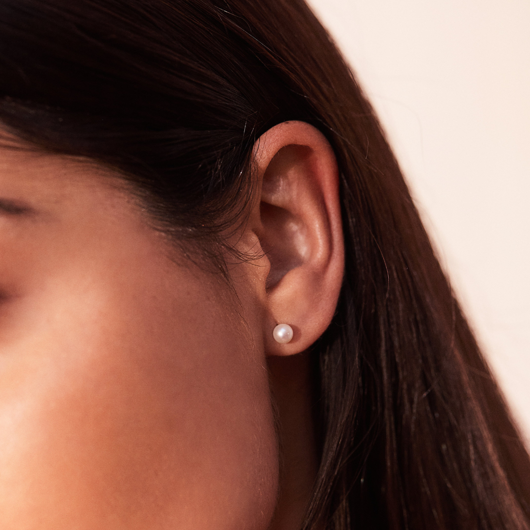 Silver single pearl stud earring close up in a ear lobe