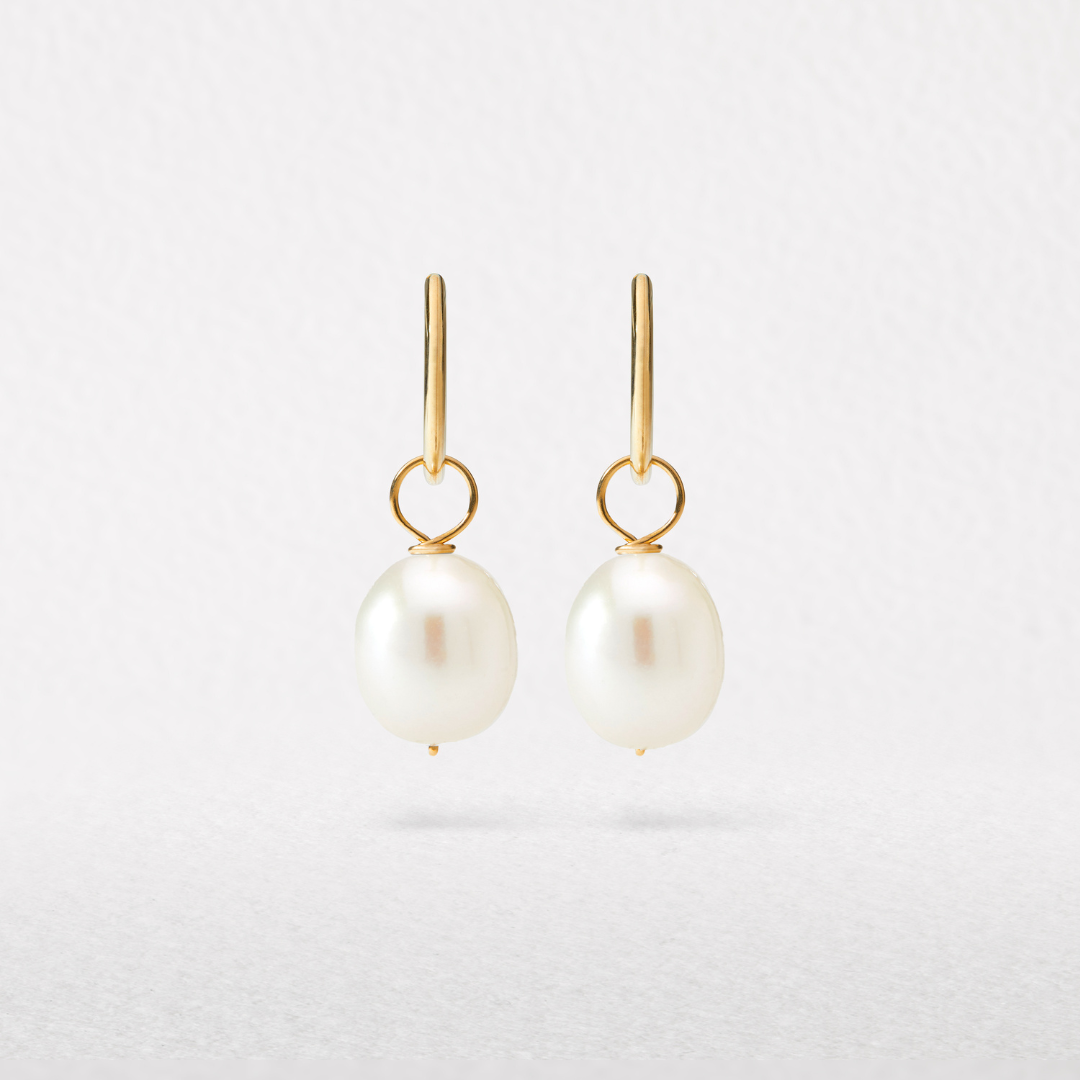 Solid gold large pearl drop hoop earrings hovering on a white background