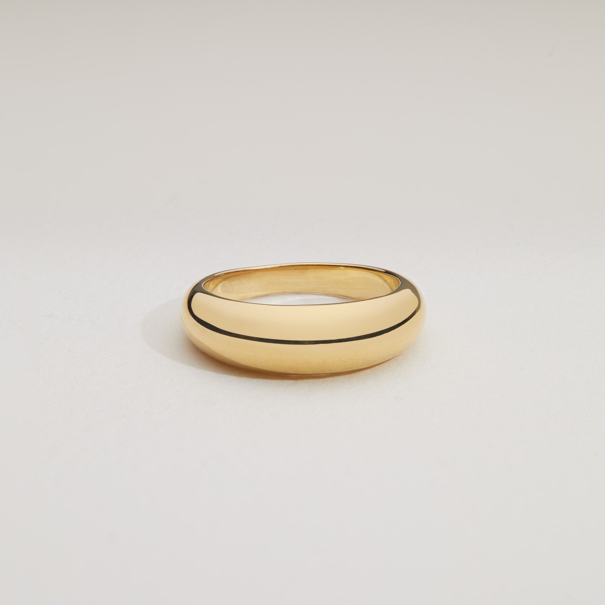 Gold plain dome ring on a white surface