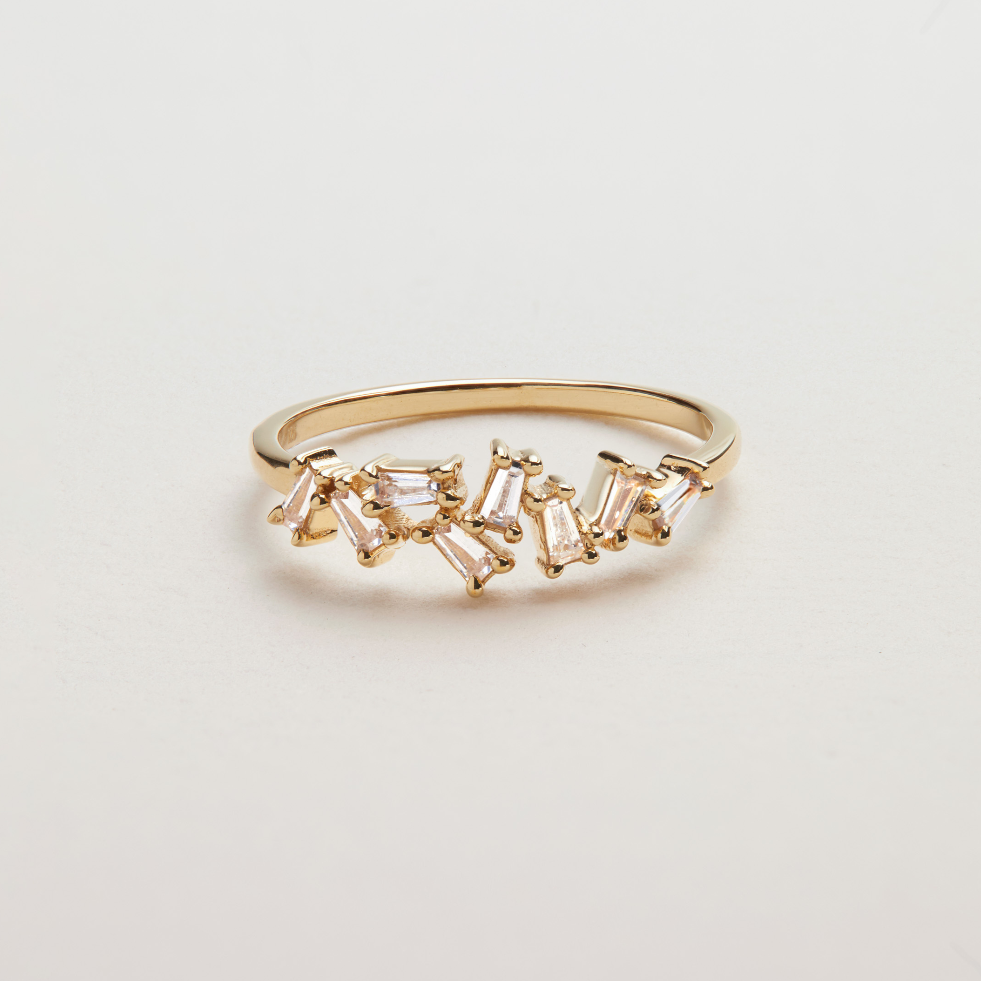 Gold diamond style baguette ring on a white surface
