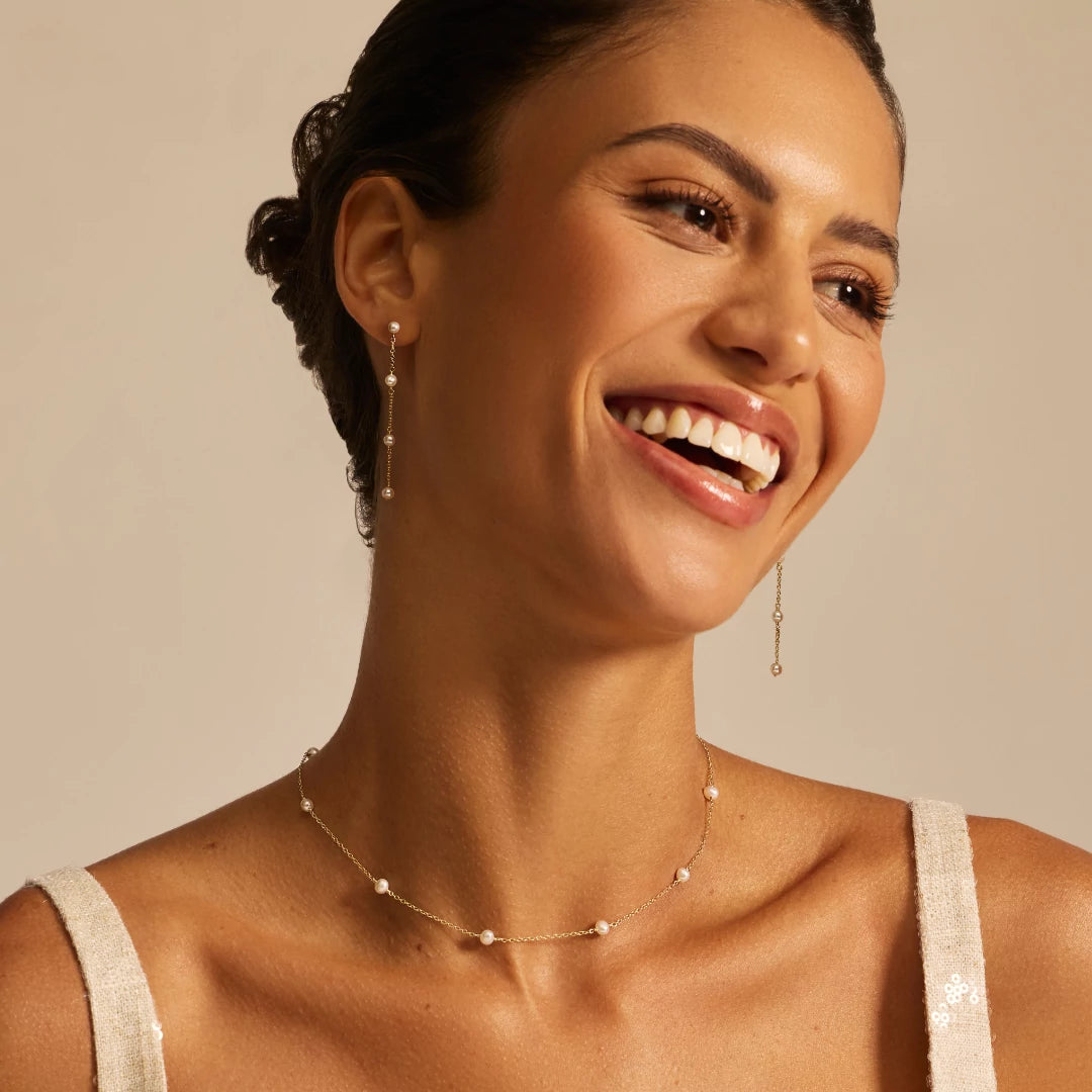 Woman wearing pearl jewelry against a beige background