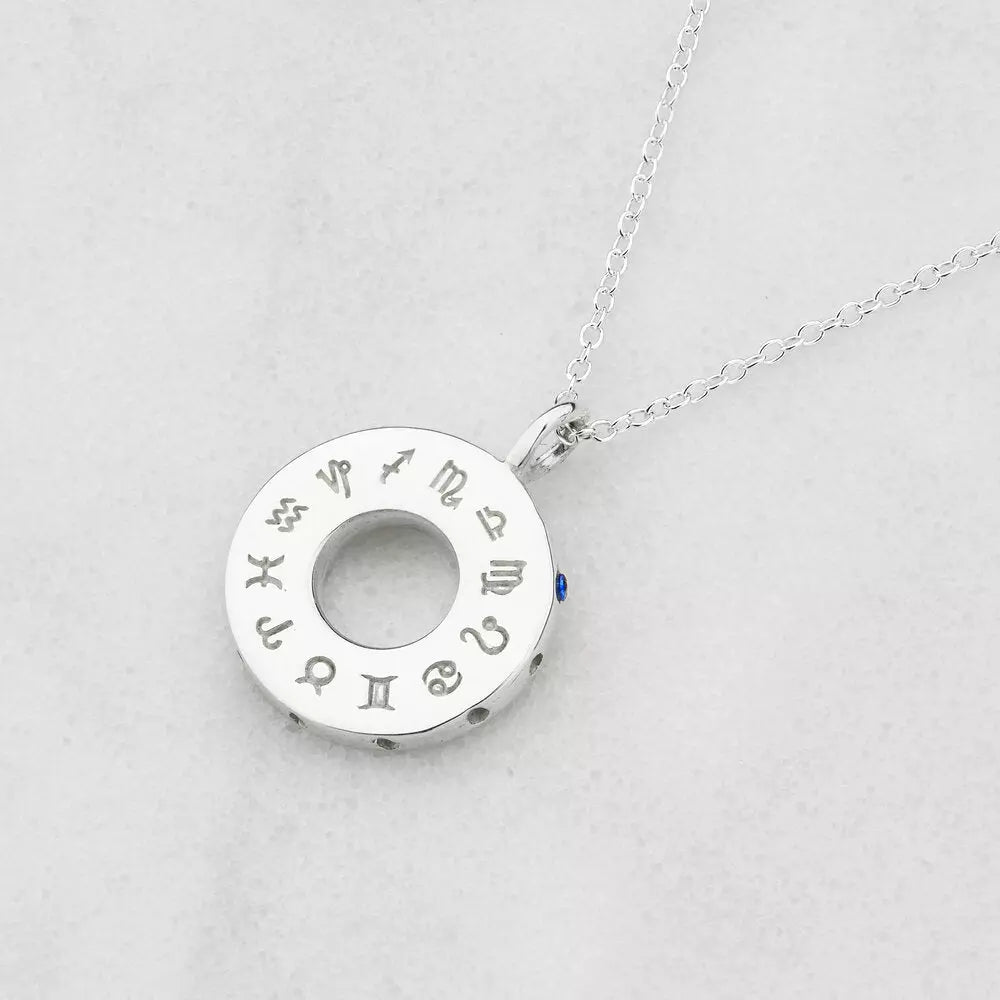 Silver zodiac birthstone necklace on a marble surface
