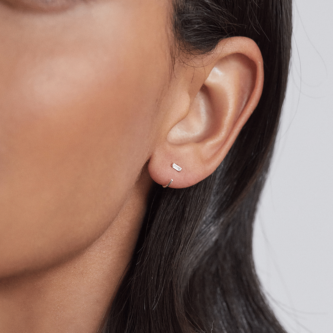 Silver diamond style baguette lobe hoop earring in one ear lobe 