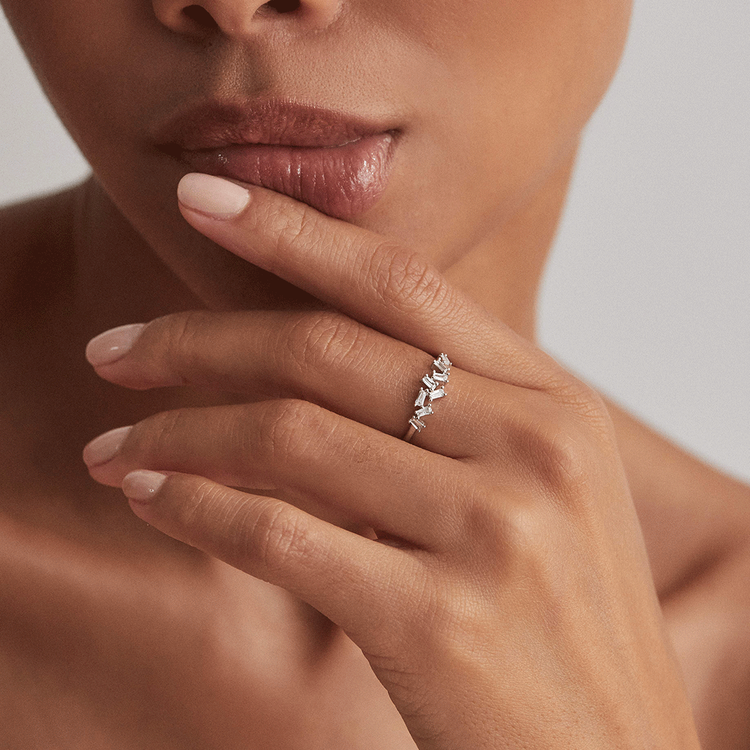 A silver diamond style baguette ring on one finger