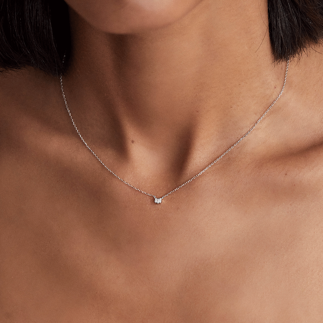 Silver triple baguette diamond necklace around a neck