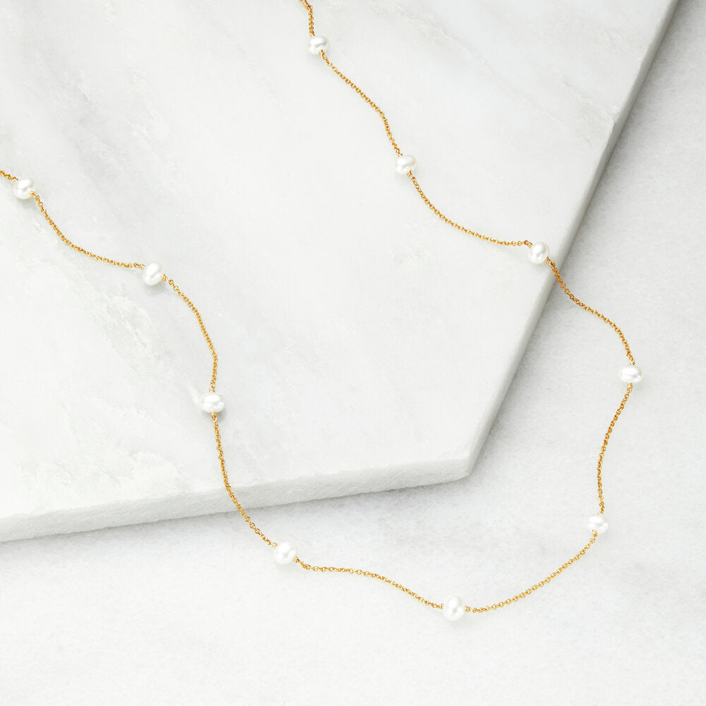Gold ten pearl choker on marble surfaces
